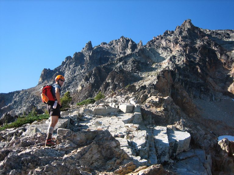 A mountain climber pauses on a ridge below Katsuk Peak