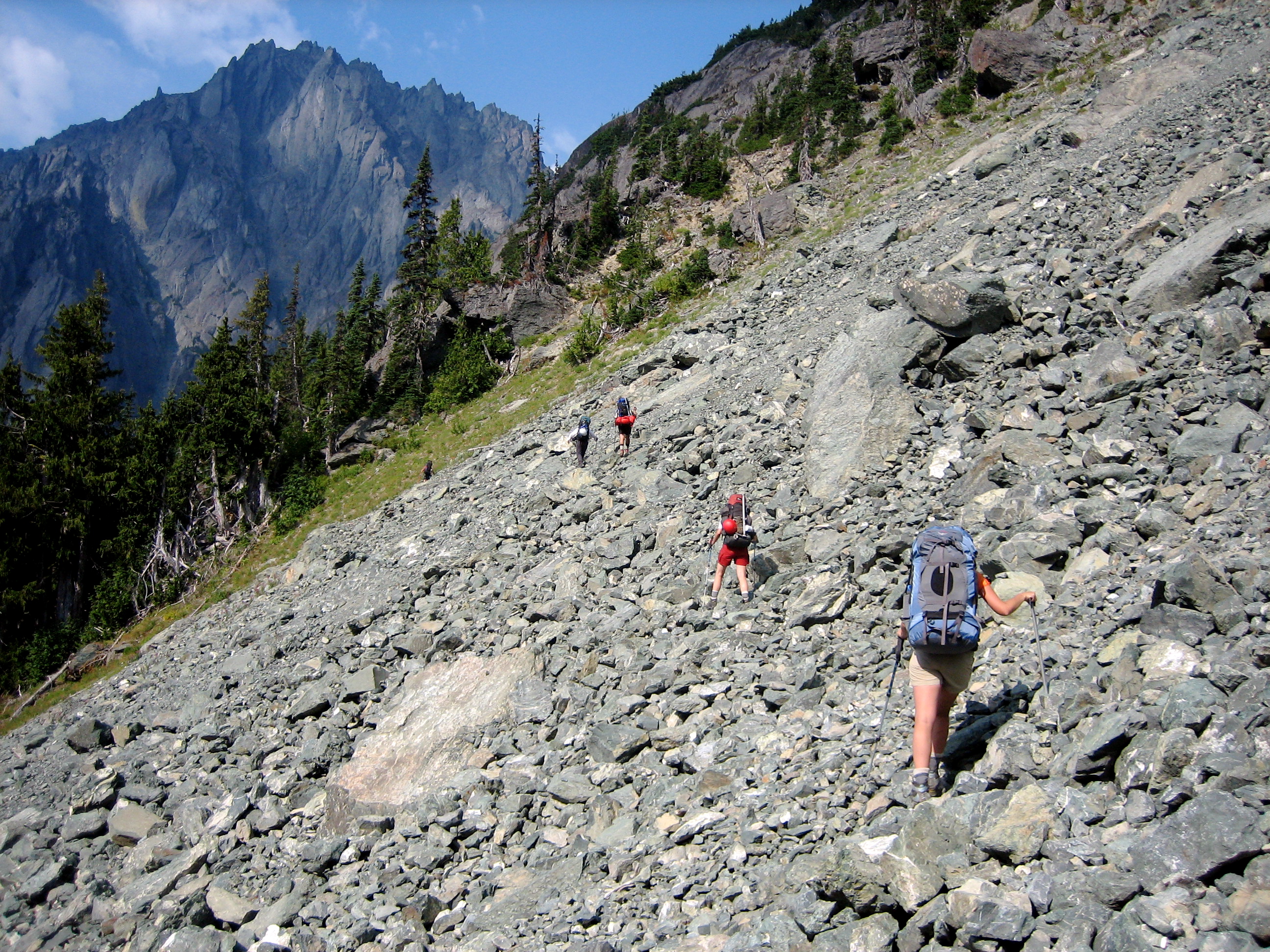 backpackers hiking through the rocky scree contouring around Mt Mystery with the Olympic Mountains