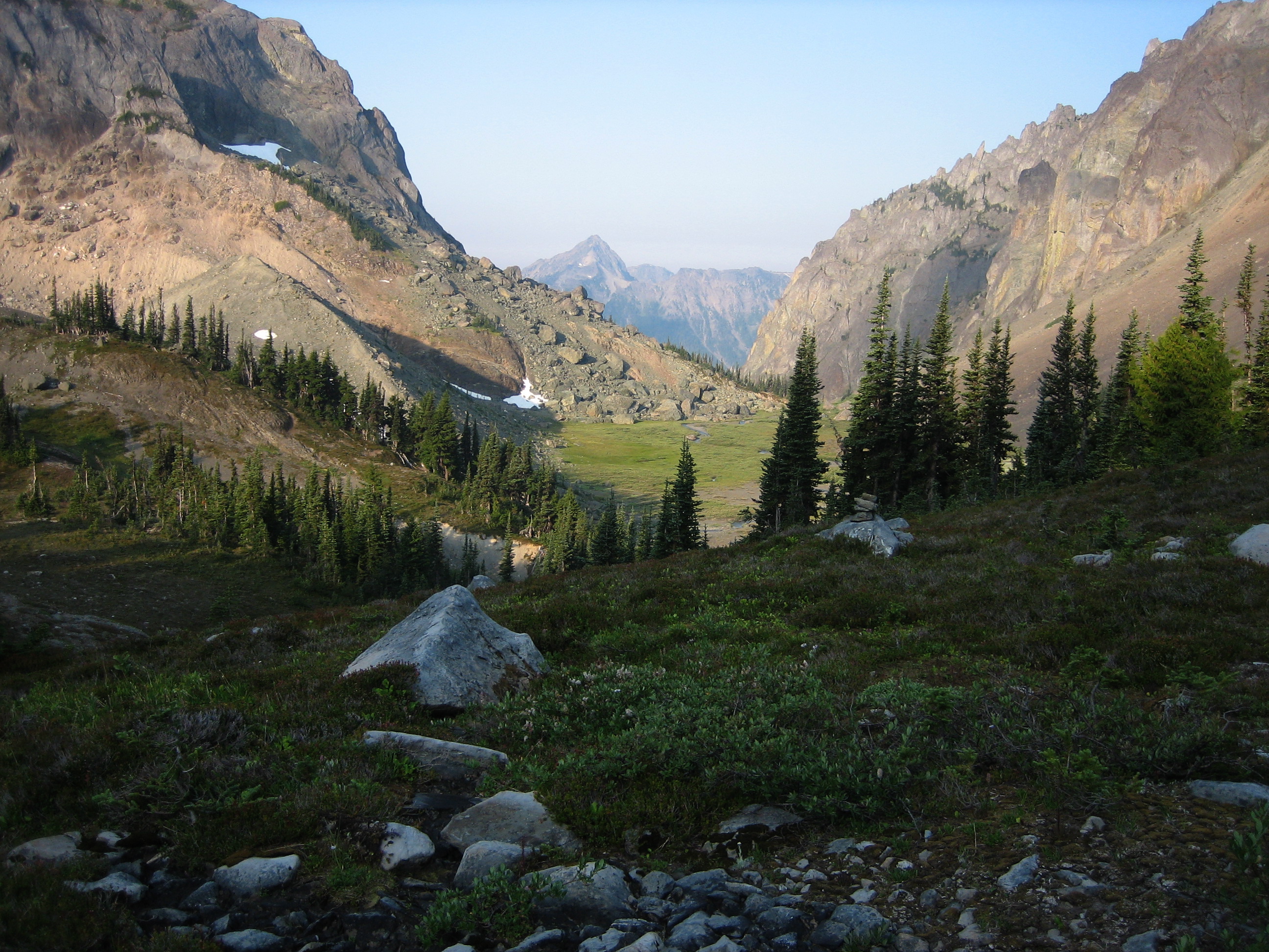 Lower Deception Basin with grasses and rocky boulders and distant view of the Olympic Mountains