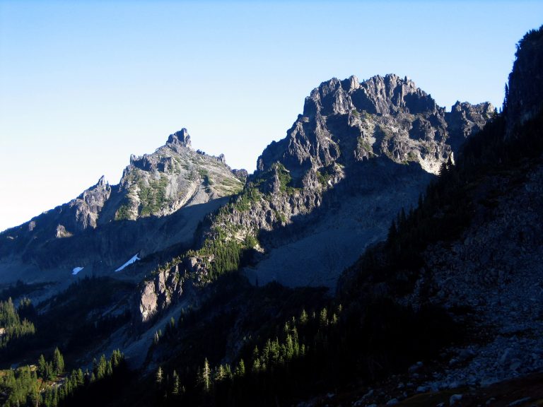 Two pointed peaks of Sluiskin Mountain stand above a forest slope