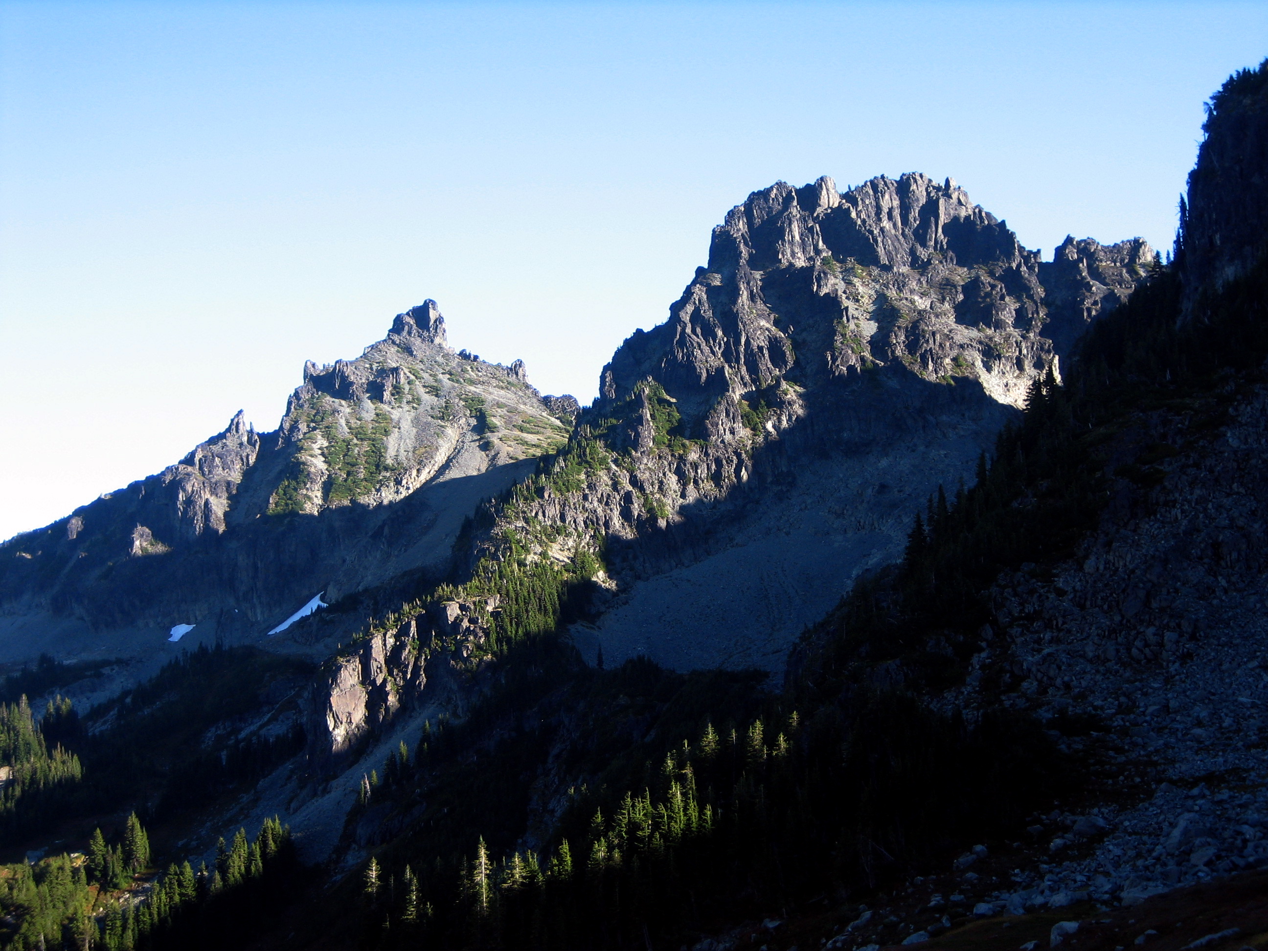 Two pointed peaks of Sluiskin Mountain stand above a forest slope