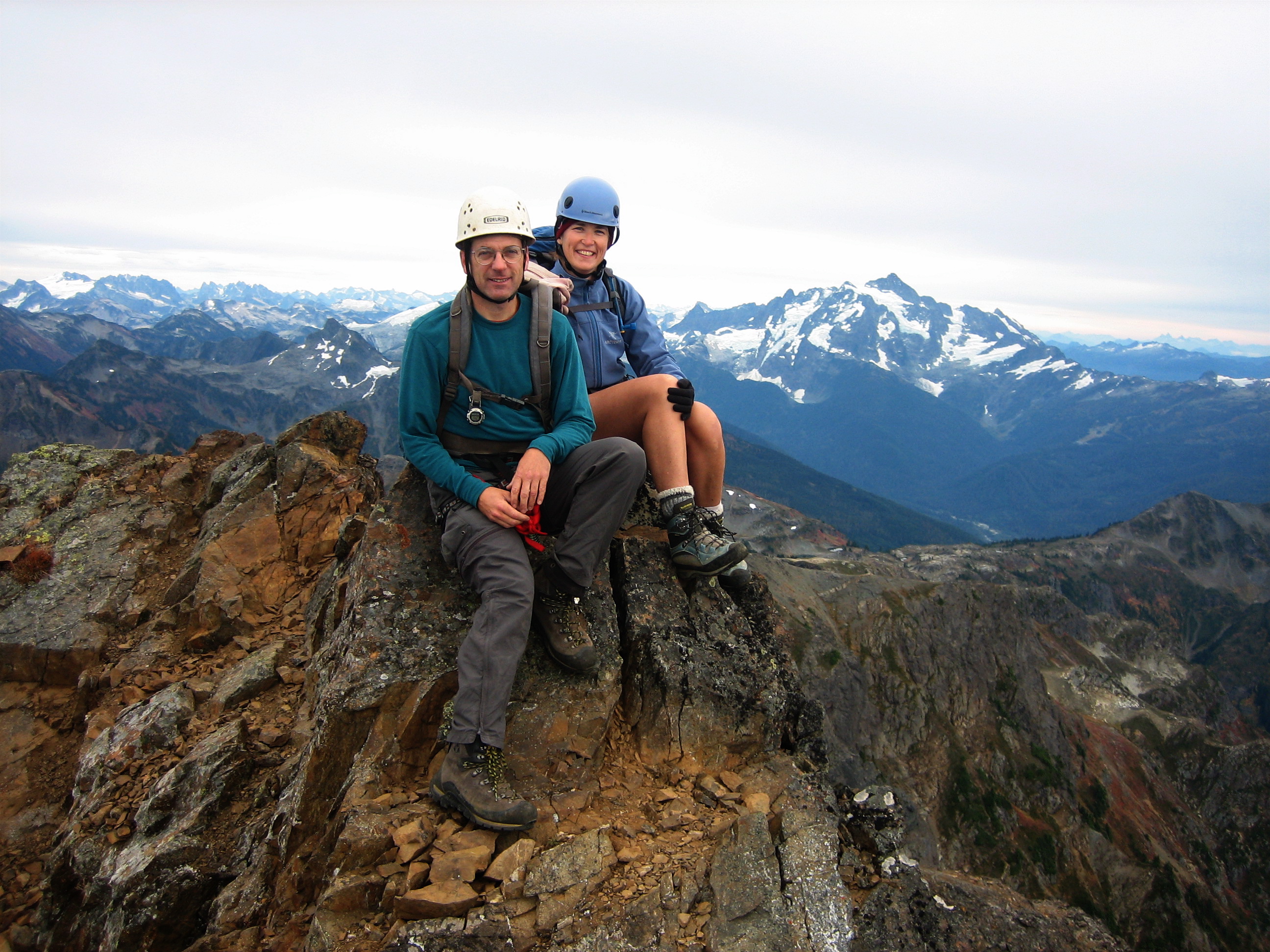 mountain climbers on the summit horn of Tomyhoi Peak in the A rock climber scrambles a steep face above the Tomyhoi Glacier heading to the summit of Tomyhoi Peak in the Nooksack Mountains