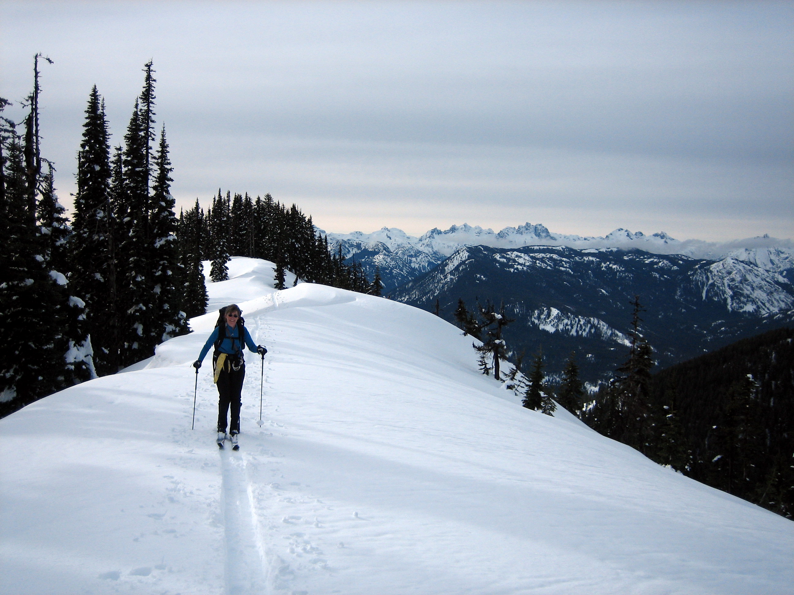 A backcountry skier glides along a flat ridge crest to Middle Jolly Knoll