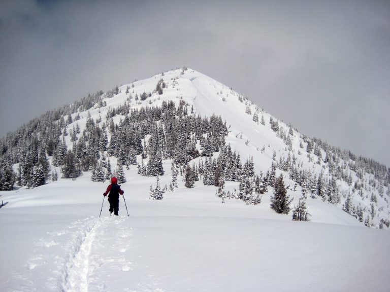 A backcountry skier traverses a ridge crest toward Silver King Peak