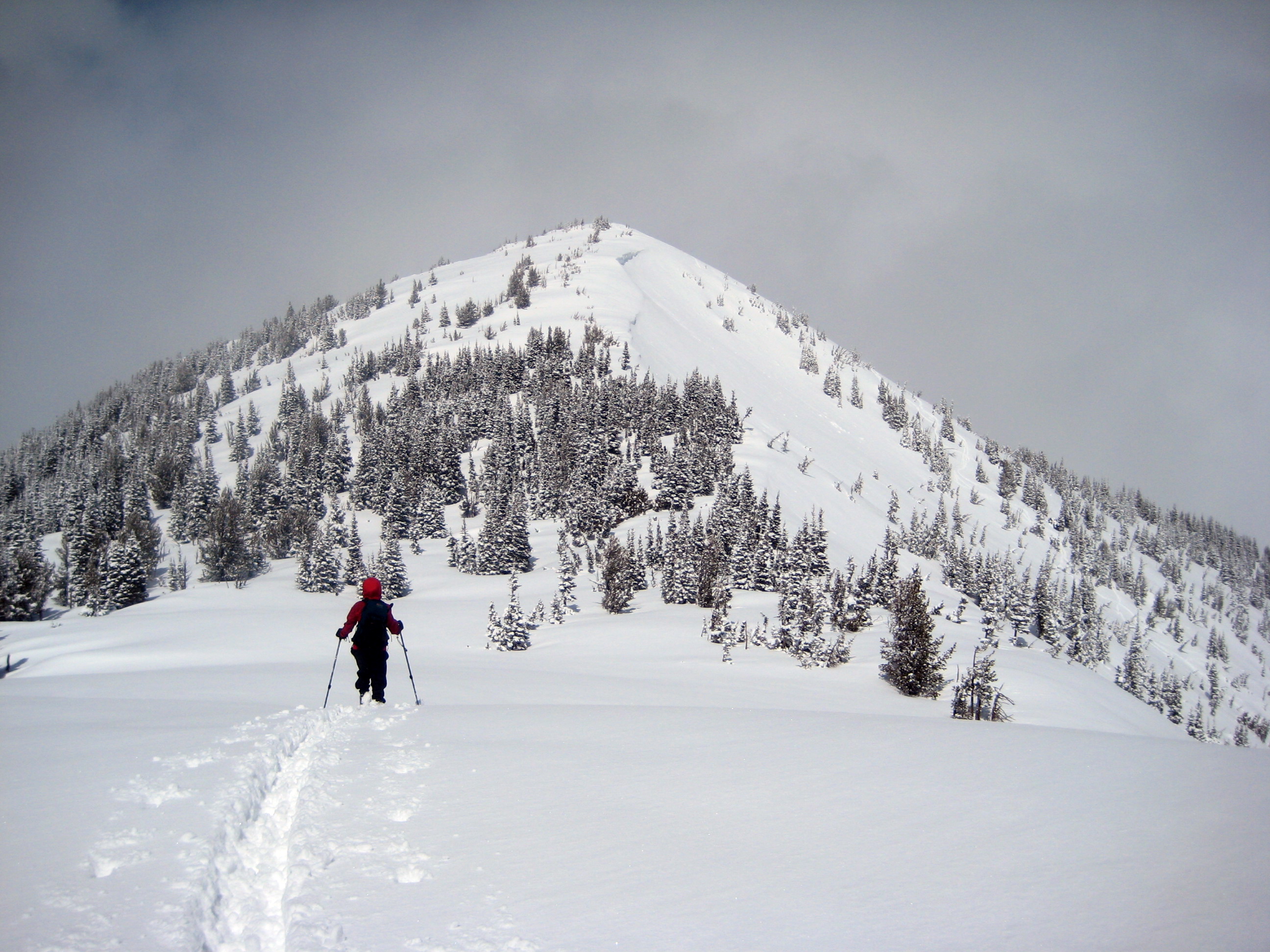 A backcountry skier traverses a ridge crest toward Silver King Peak