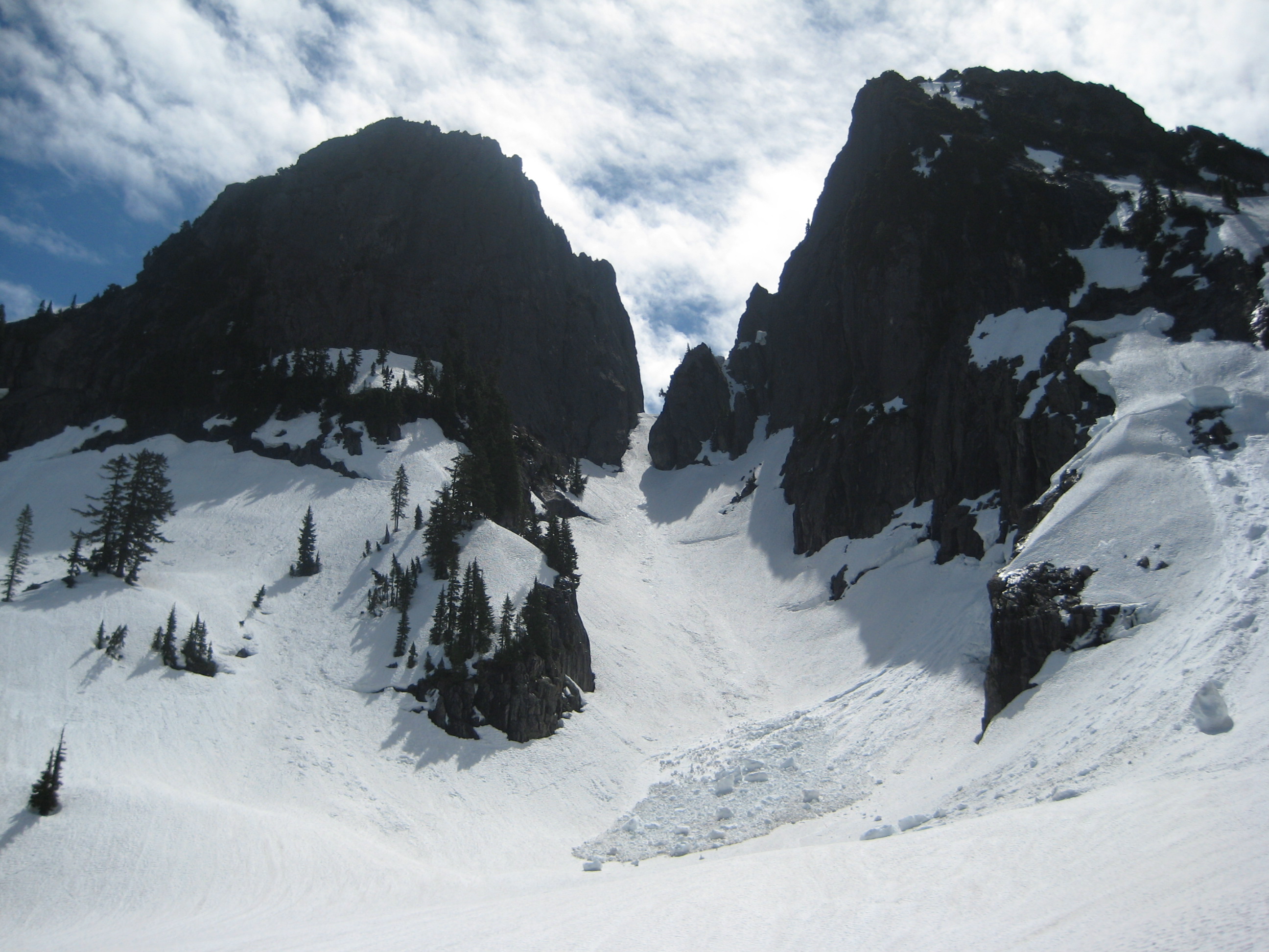 A snow chute extends upward between two rocky peaks of Mt Garfield