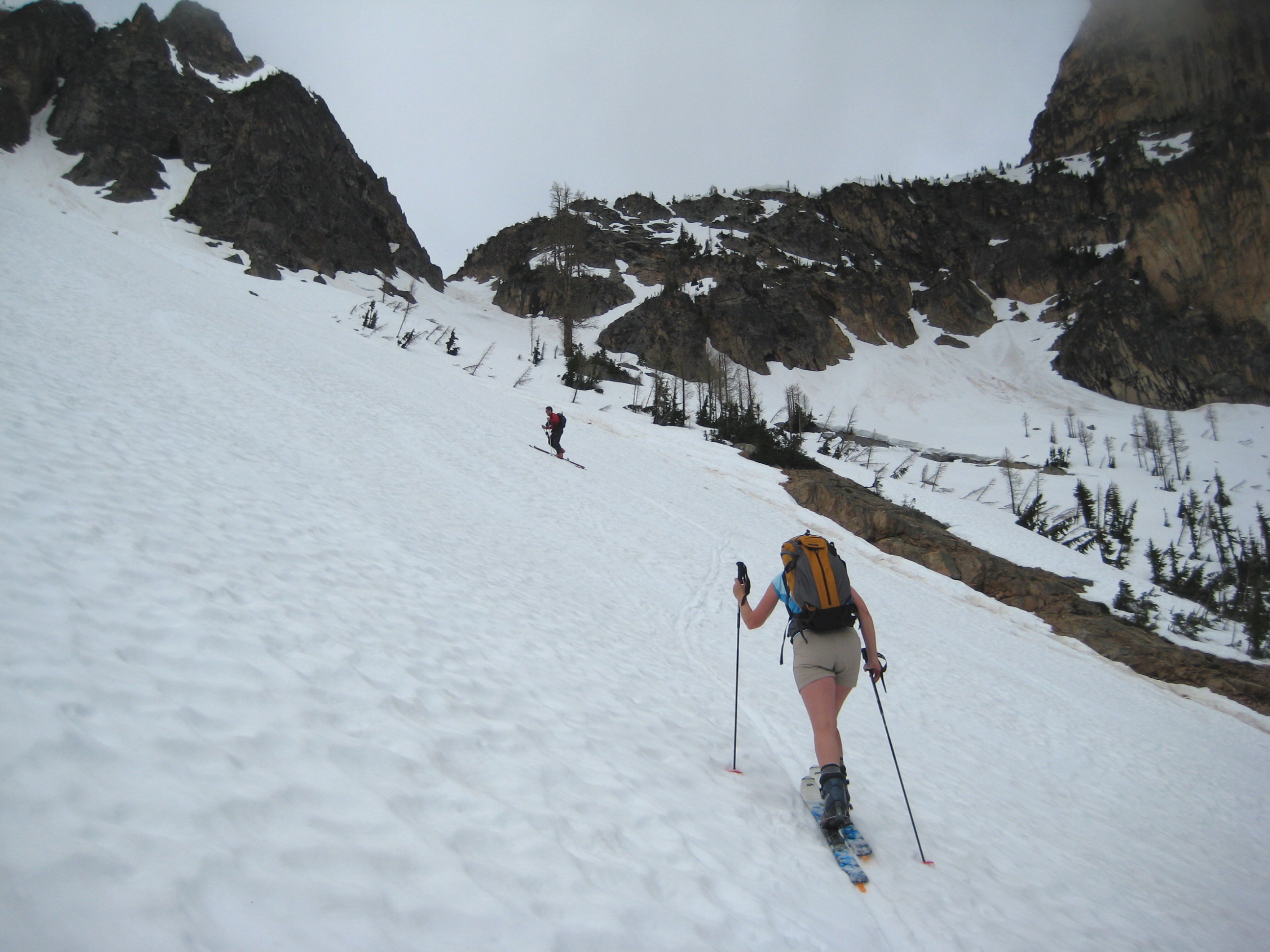 Two backcountry skiers ascend a steep snow chute below Cornice Peak in the North Cascades