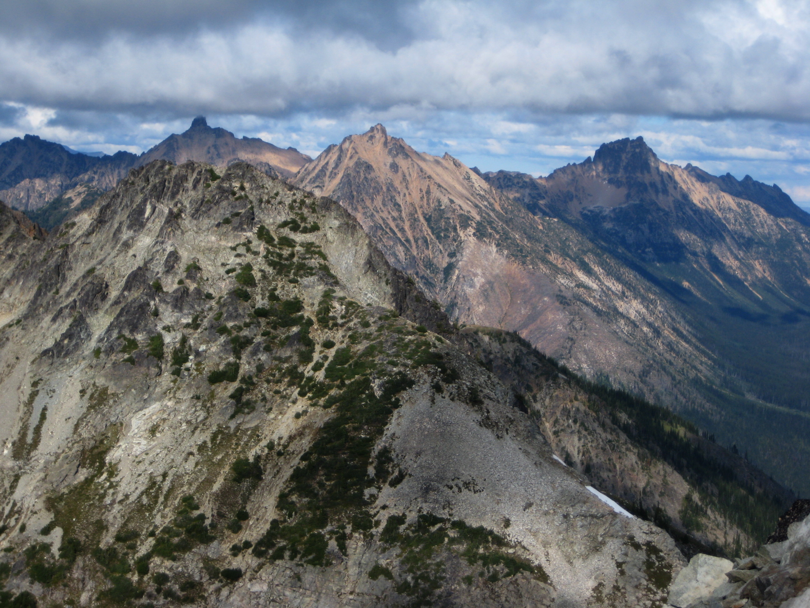 Golden Horn Peak, Mt Hardy, and Tower Mountain in the Upper Methow Mountains fill the distant sky line with clouds over head as seen from Fisher Peak in North Cascades National Park