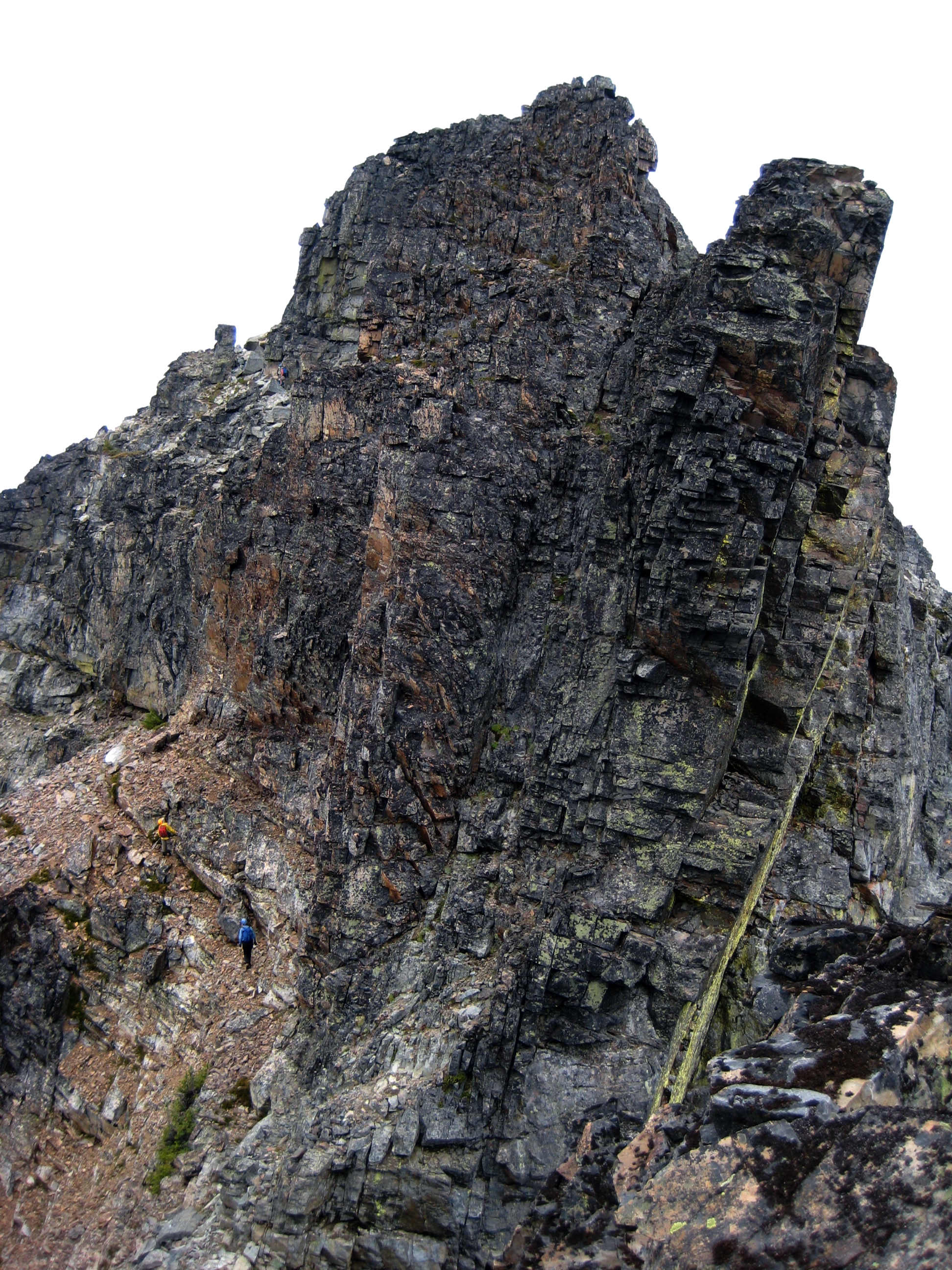 mountain climbers traversing rocky ledge below the large rocky summit horn of Mt Arriva in North Cascades National Park
