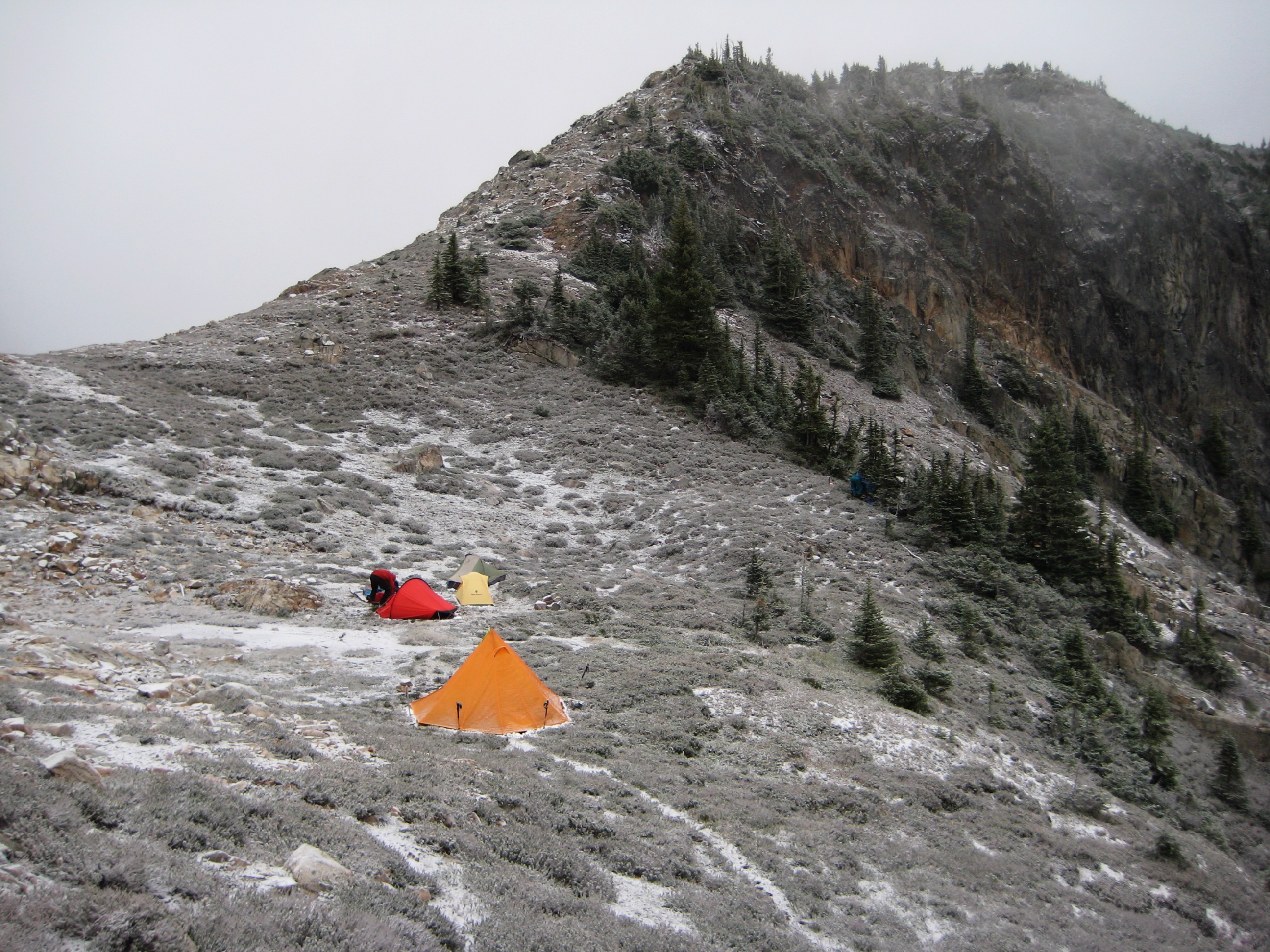 mountain climber's camp on the shoulder of Silent Lakes in North Cascades National Park dusted with snow turning the rock and heather white