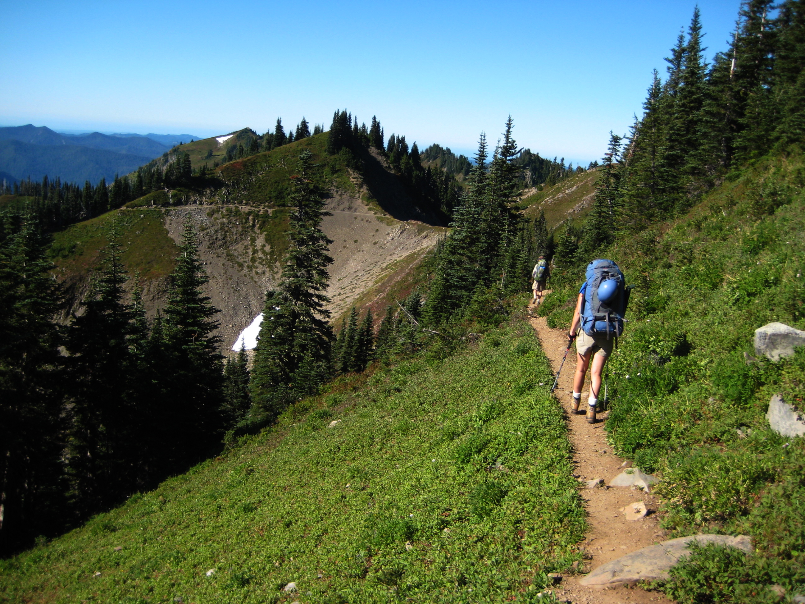 Two hikers follow a trail across the High Divide during the Seven Lakes Loop in the Olympic Mountains