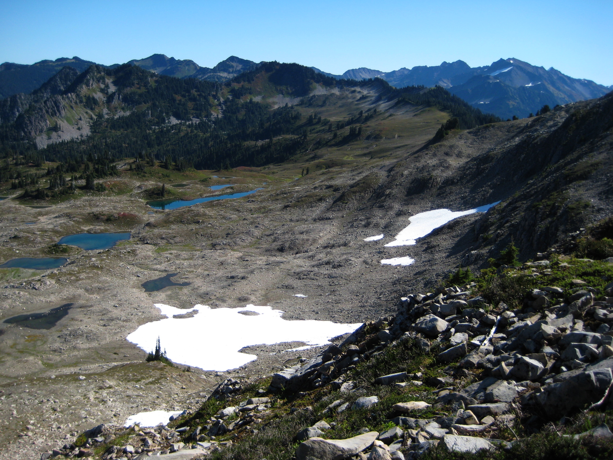 Seven Lakes Basin in Olympic National Park with linguring snow patches and rocky ridges with the Olympic Mountains in the background