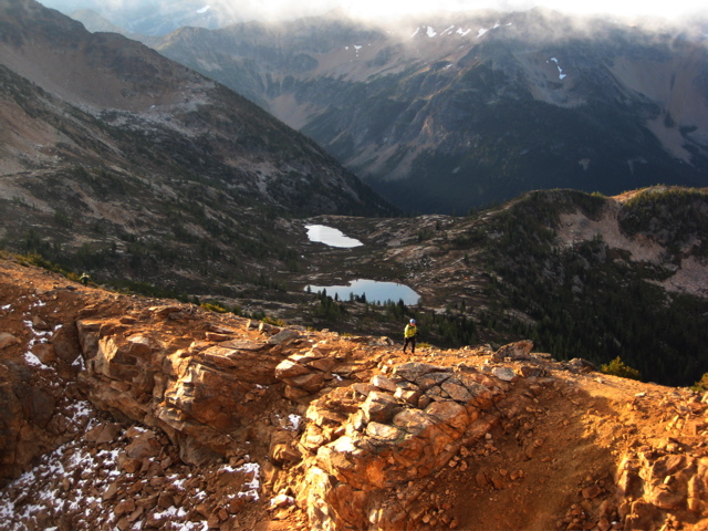 looking down on mountain climber hiking up the shoulder of Golden Horn peak in the Upper Methow Mountains with Snowy Lakes in the basin below