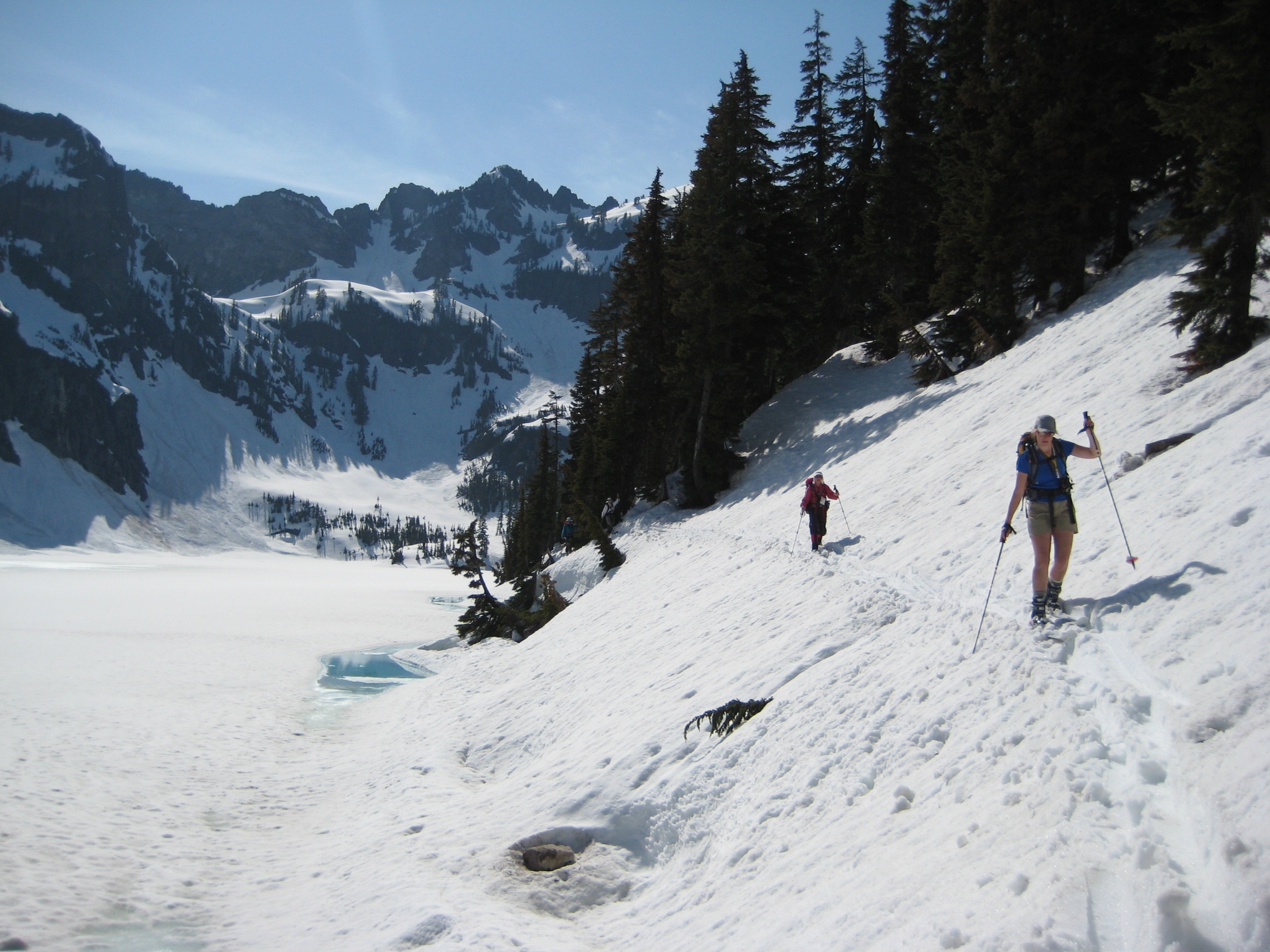 backcountry skiers traversing snow covered lake shore of Snow Lake during the Chair Peak Circumnavigation Ski Tour