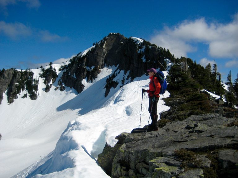 A mountain climber stands on a rocky ridge below Silver Peak near Snoqualmie Pass
