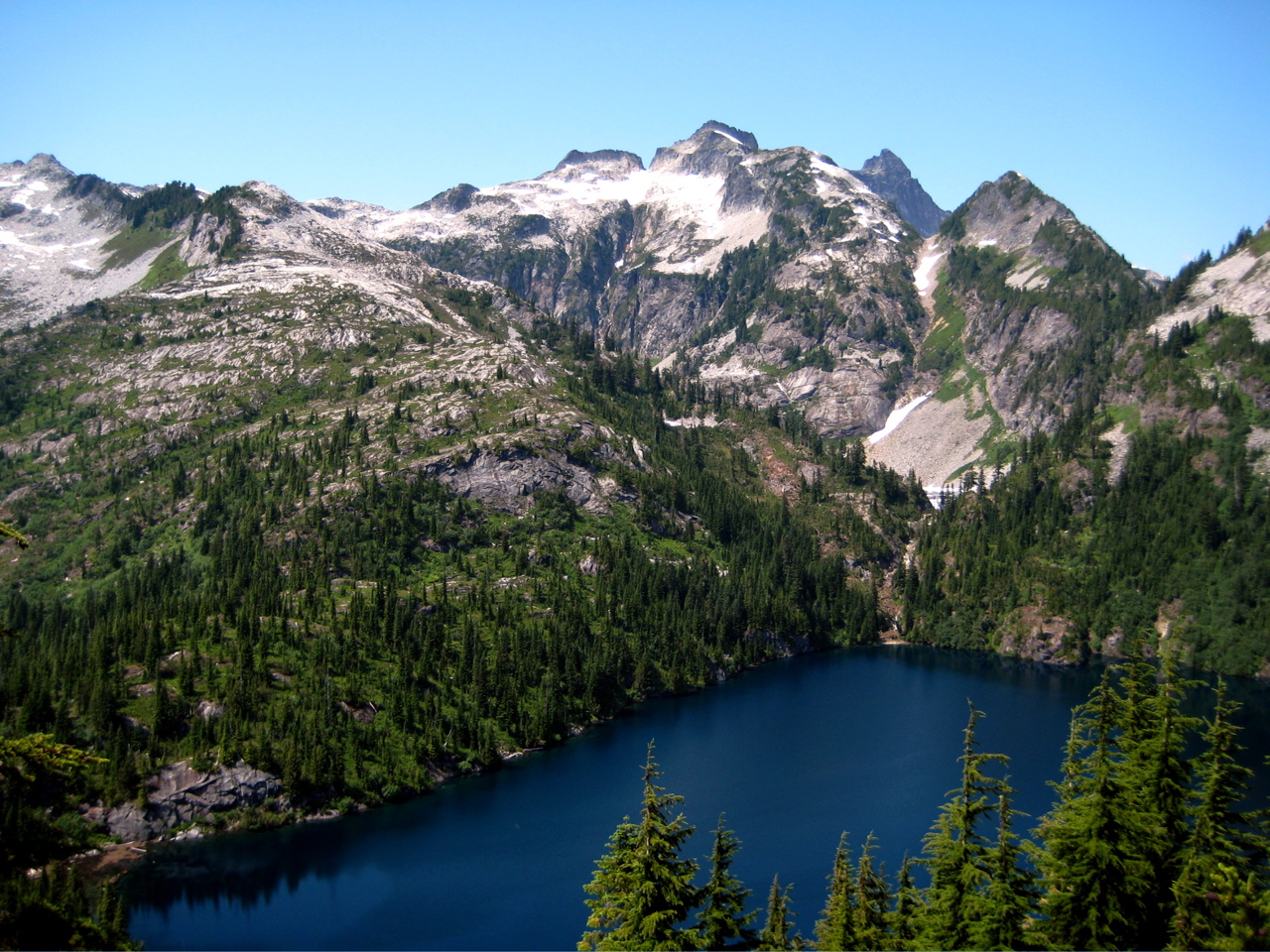 Craggy Thornton Peak stands over dark blue Thornton Lake in the Lower Skagit Mountains