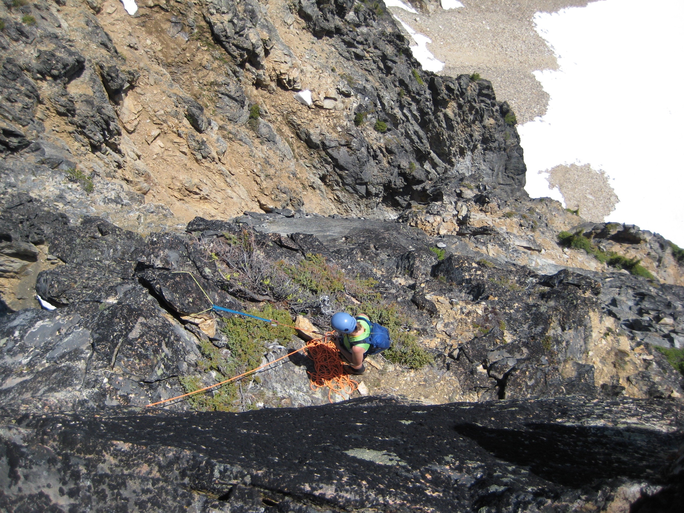 mountain climber belaying in the rocks from below the Tupshin Peak summit in the Glacier Peak Wilderness