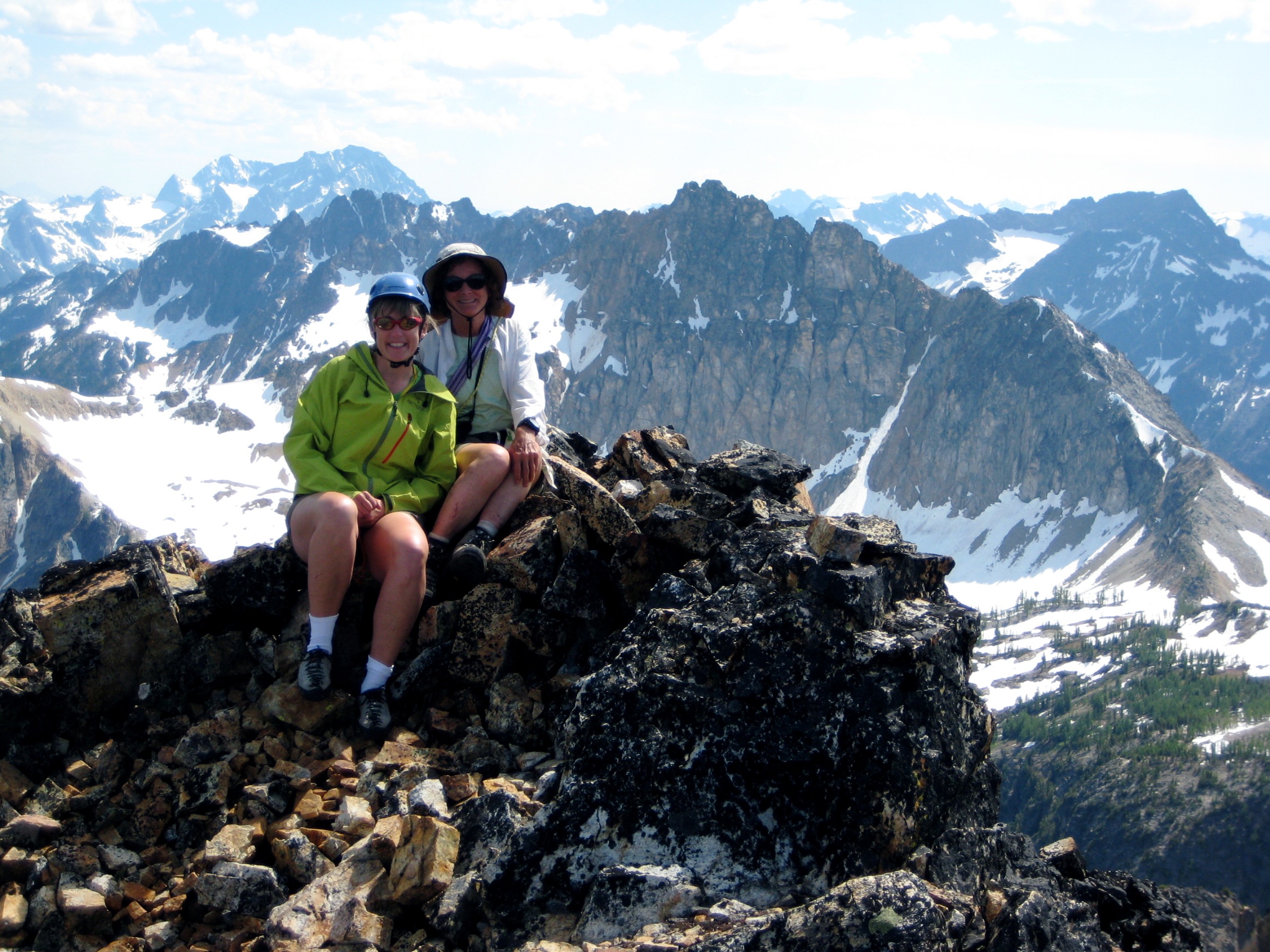 mountain climbers on the rocky summit of Glacier Peak Wilderness with the Stehekin Mountains in the background