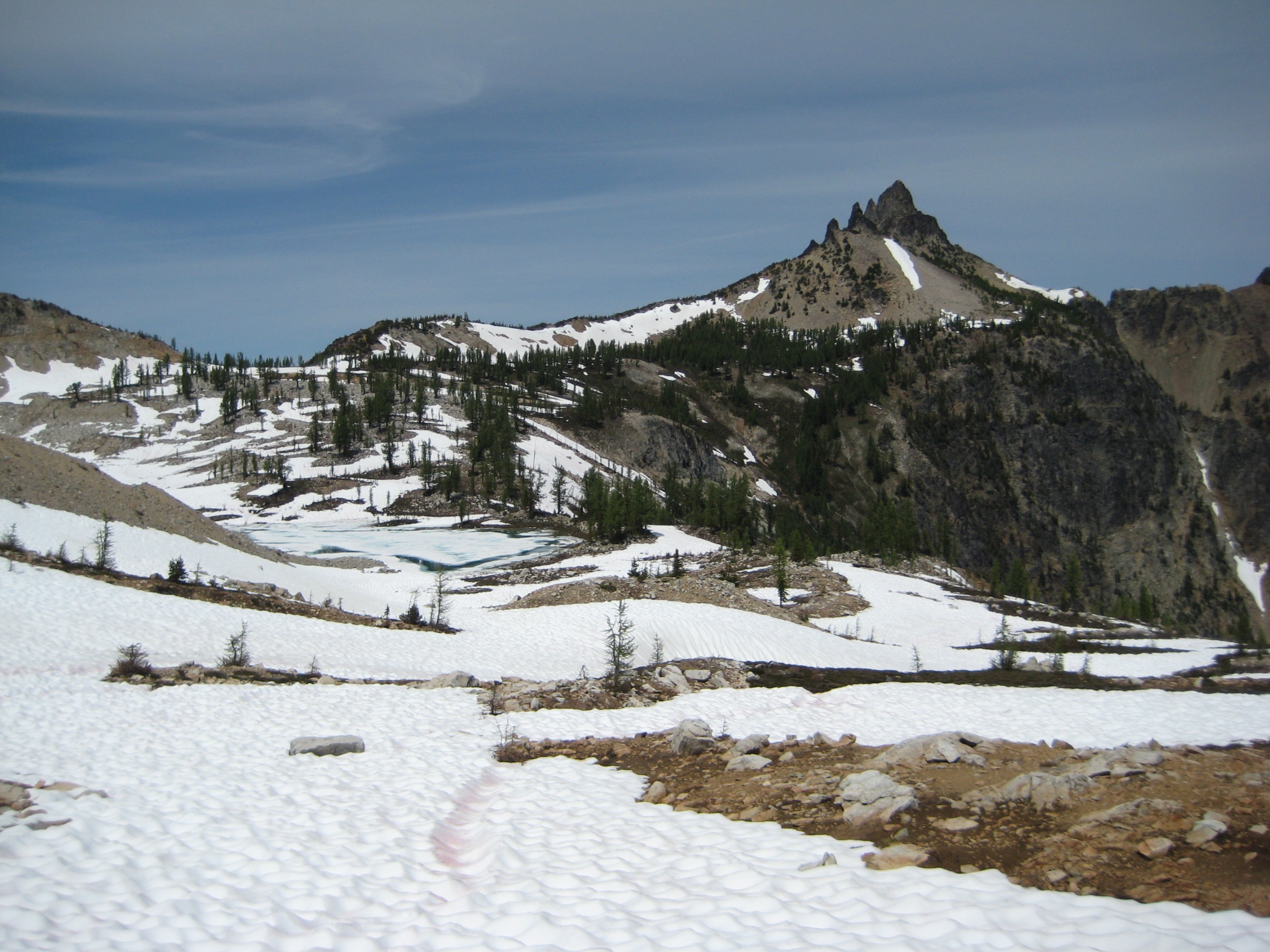 snow filled Bird Lake Basin with the sharp rocky summit horn of White Goat Peak in the Glacier Peak Wilderness