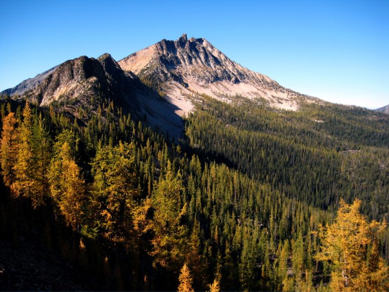 Green and gold trees sweep upward to the rocky summit of Lake Mountain