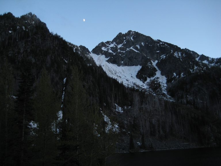 The moon sets over the top of triangular Axis Peak in the Icicle Mountains