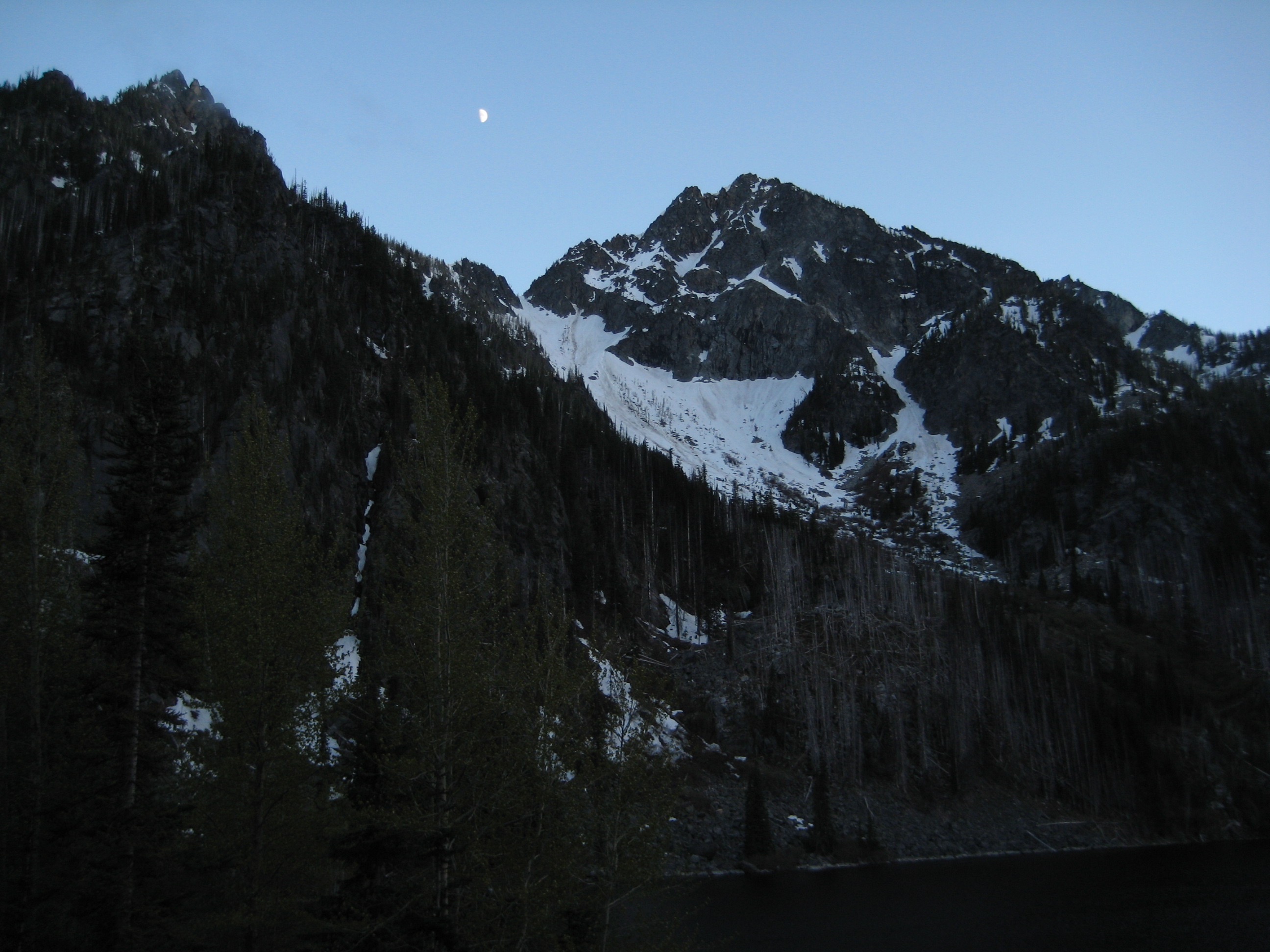 The moon sets over the top of triangular Axis Peak in the Icicle Mountains