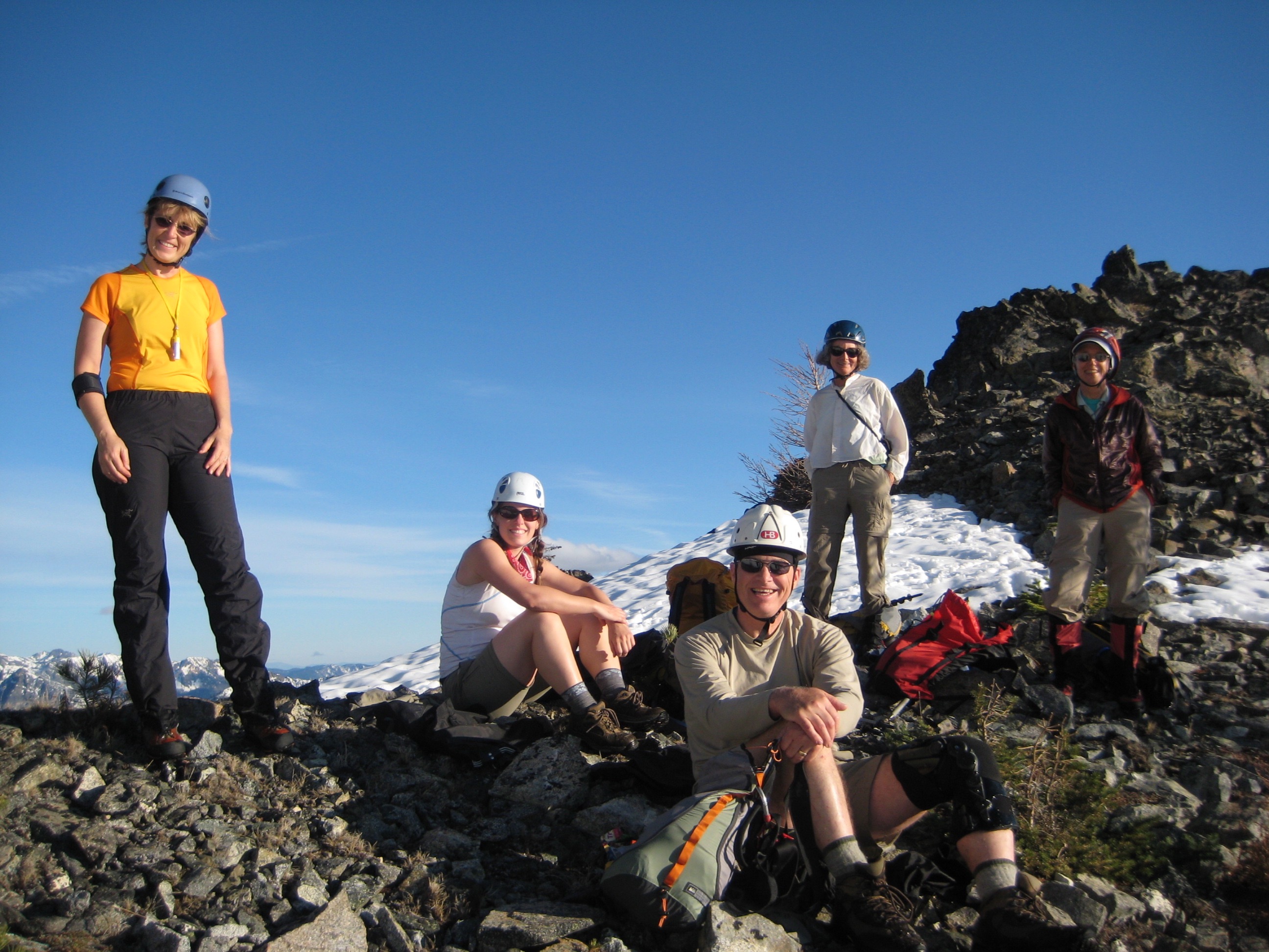 mountain climbers take a break in the rocks on the shoulder of Main RIddle Peak in the Stehekin Mountains in Glacier Peak Wilderness
