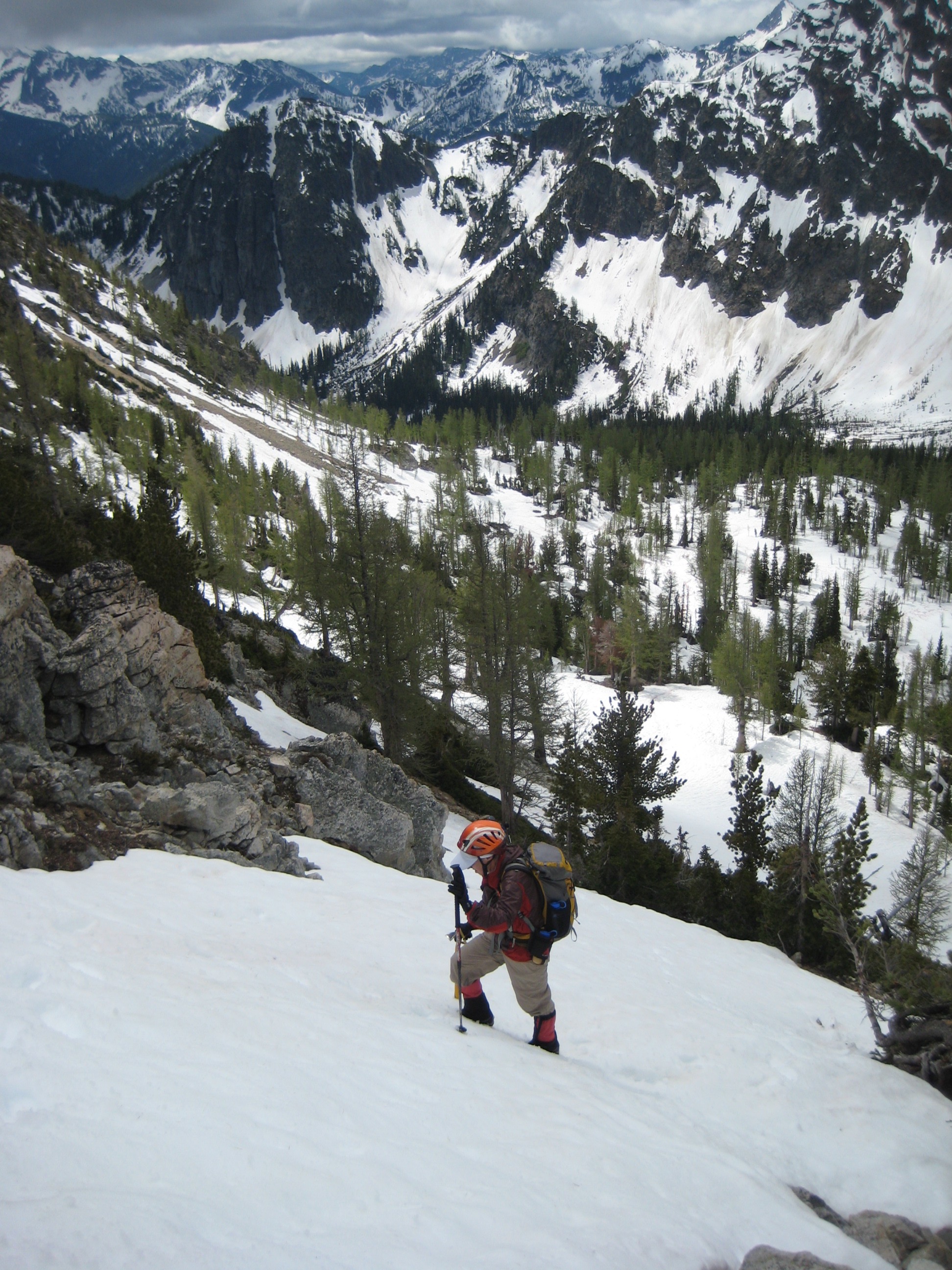 looking down on mountain climber booting up snow field with a snow field valley in the background and the Stehekin Mountains 