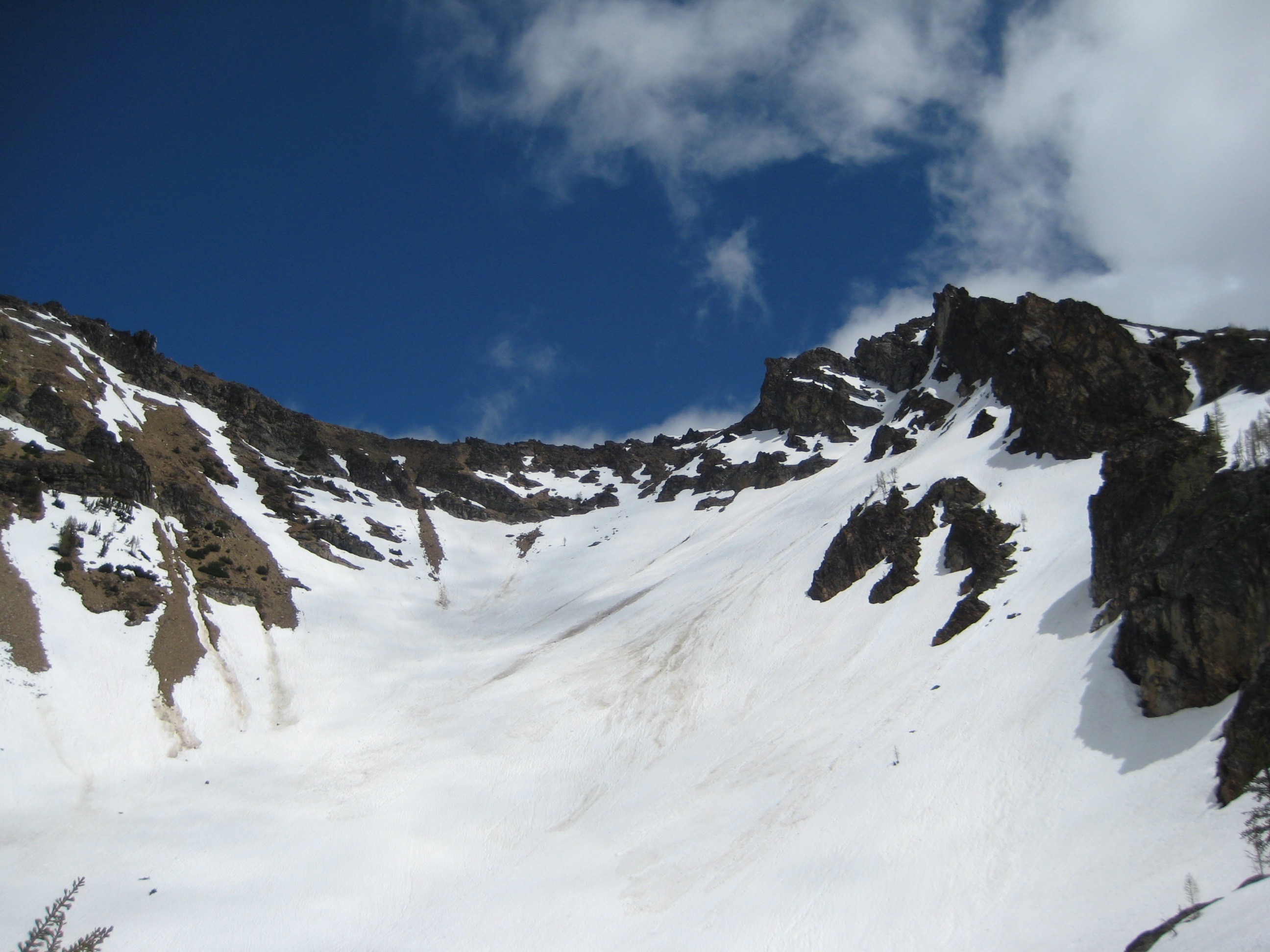 rocky ridge of Flora Mountain in the Glacier Peak Wilderness sits high above snow filled basin in the Stehekin Mountains