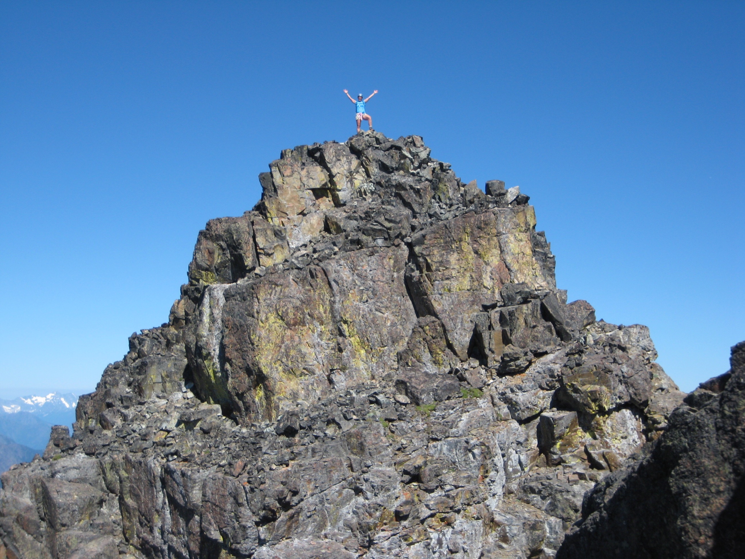 A mountain climber waves from the rocky summit of Mt Ballard