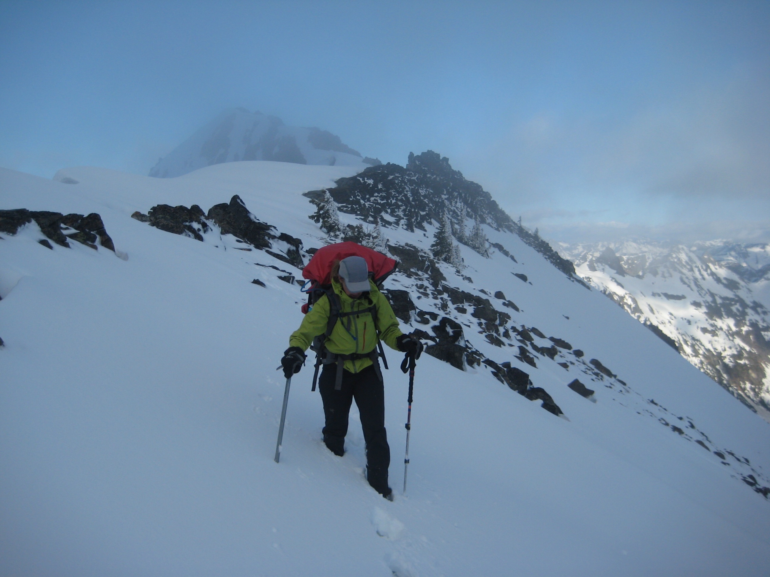 mountain climber traversing steep snow slope to Mesahchie Col with Ragged Ridge in the background