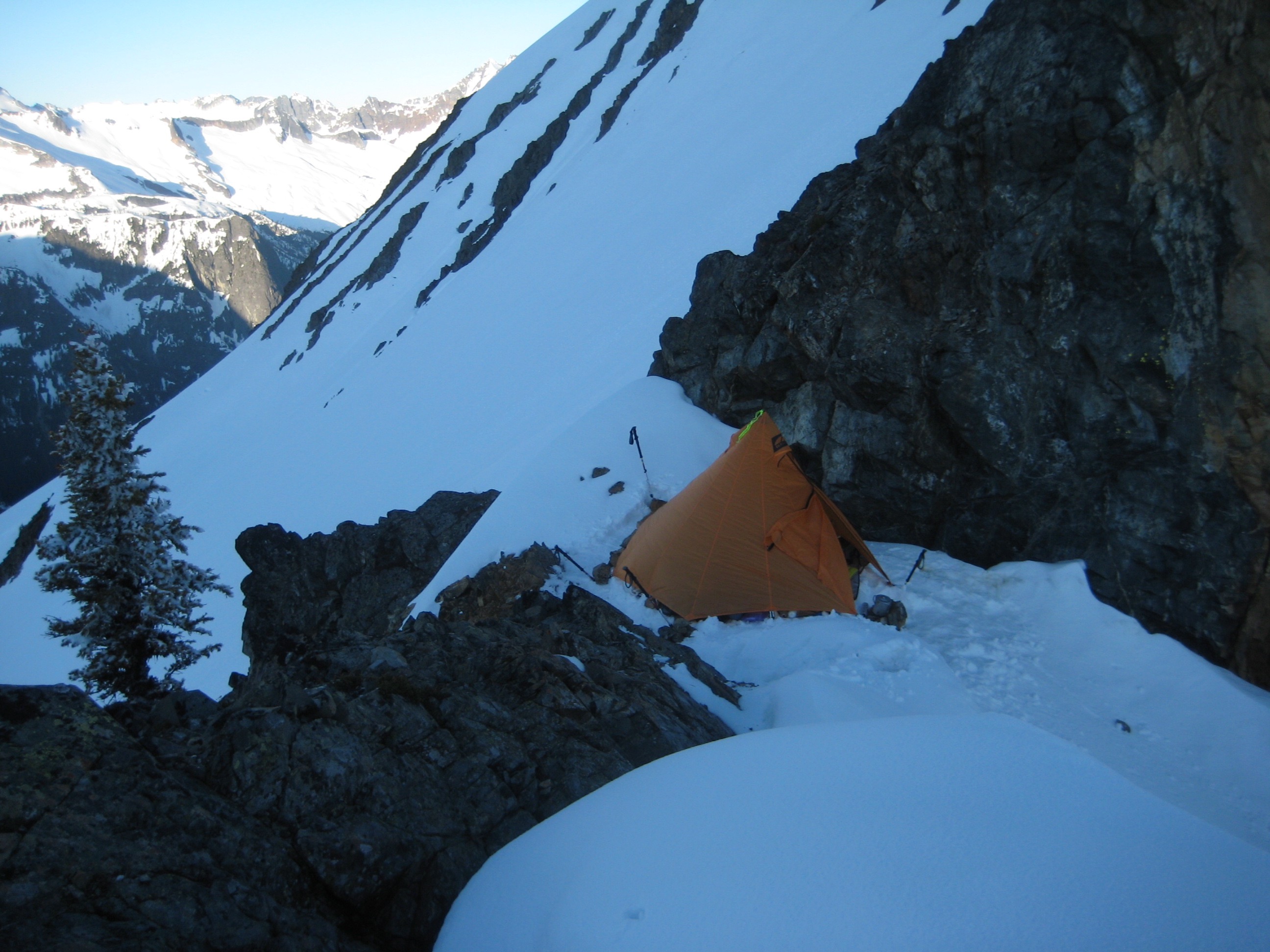 mountain climbers camp on snow patch between rocky slopes at Mesahchie Col in the North Cascades