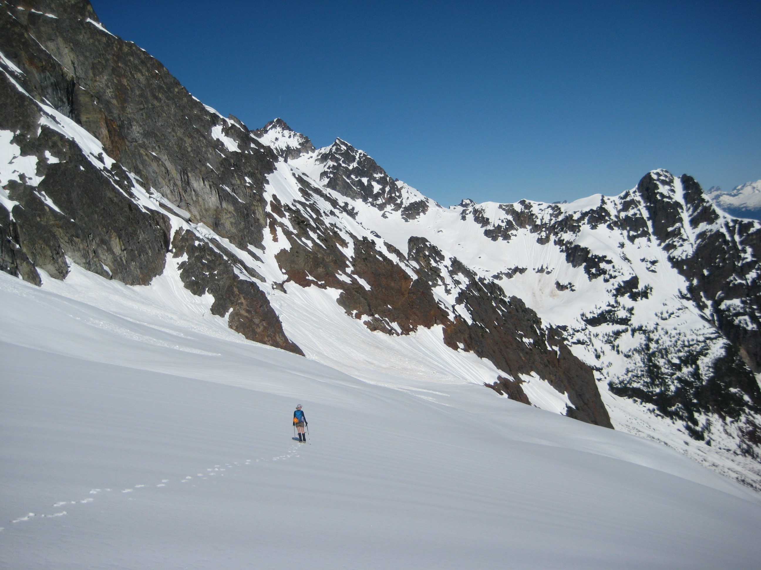 looking down at mountain climbers traversing Mesahchie Glacier with snowy rock rib in the distance