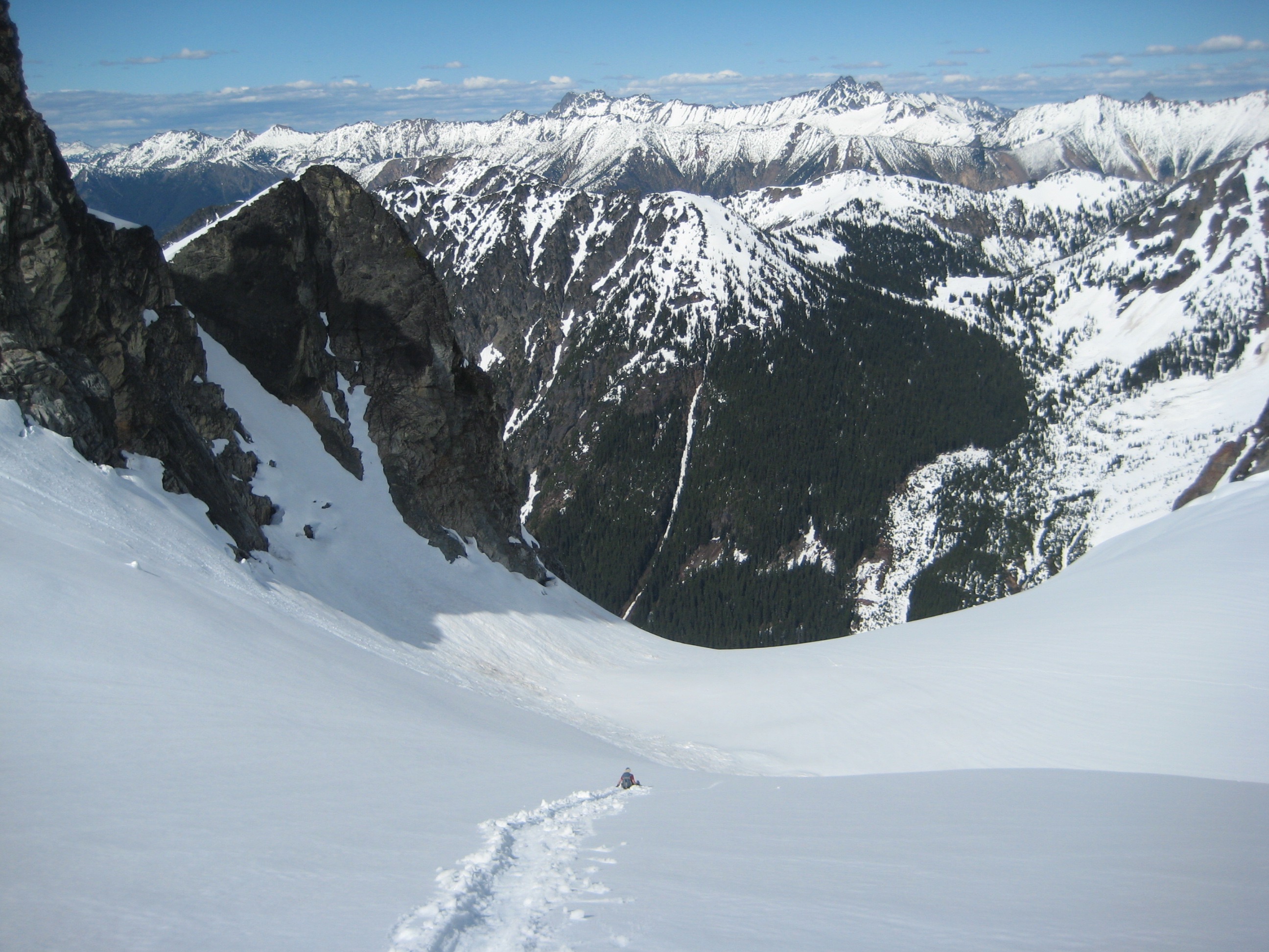 mountain climber glissading Upper Katsuk Glacier in the North Cascades with snow capped mountains in the distance
