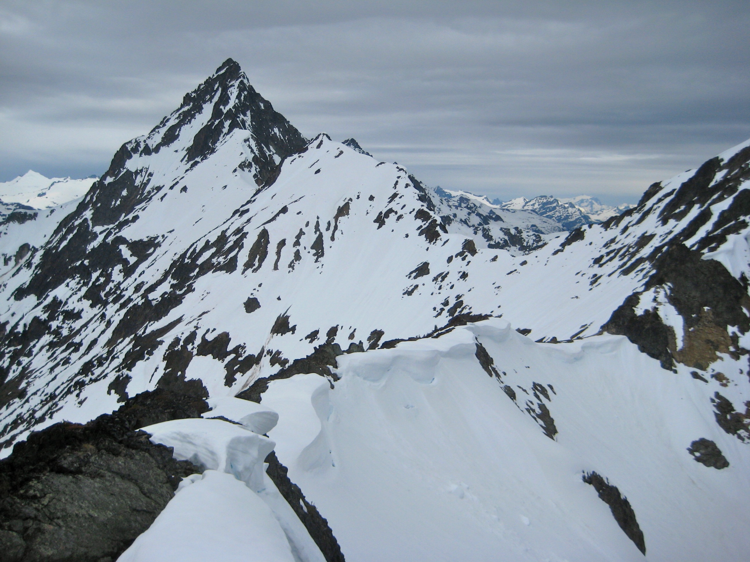snow covered Mesahchie Peak and Mesahchie Col from Ragged Ridge in the North Cascades