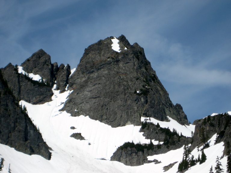 The black rock of Chair Peak towers over a snow slope
