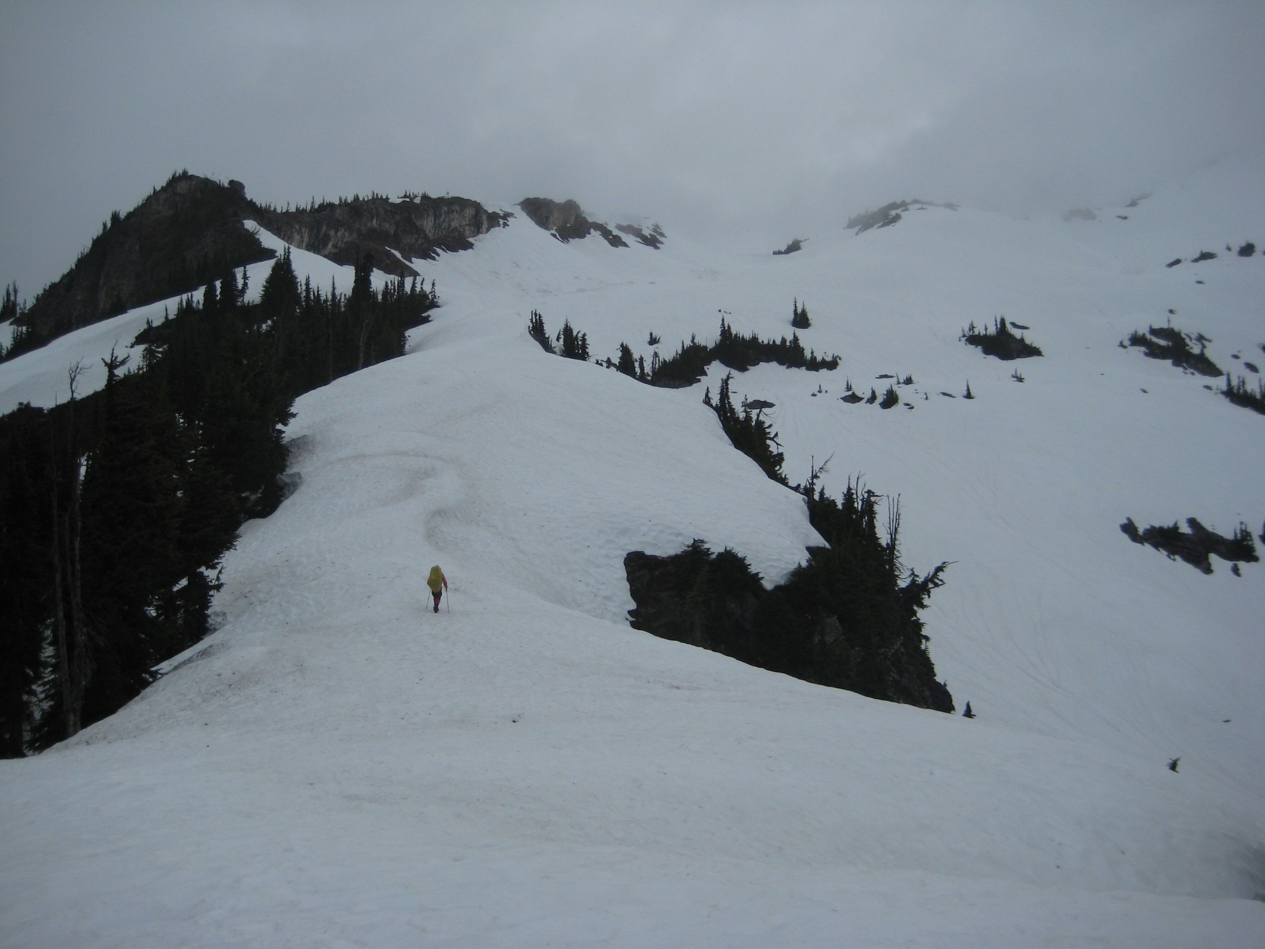 mountain climber booting up long snow slope in morning fog on Mt Prophet in North Cascades National Park