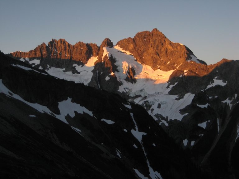 Alpenglow casts orange light on massive alpine face of Mt Formidable