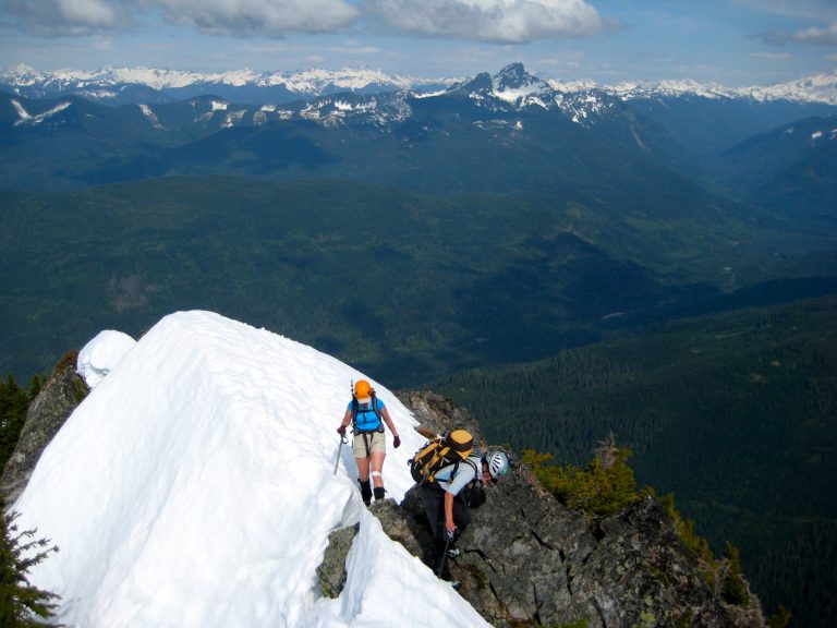 Two mountain climbers traverse a steep snowy ridge crest on Jumbo Mountain