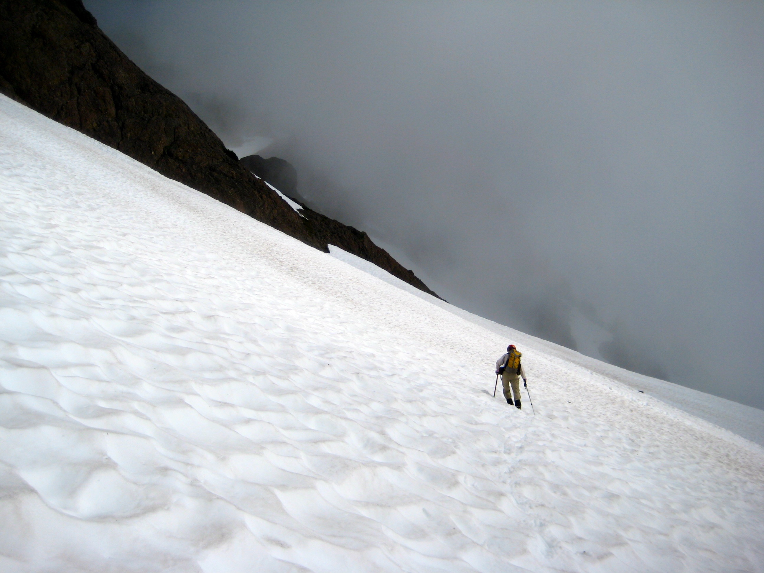 climber traversing steep snow slope heading toward North Brother in the Olympic Mountains