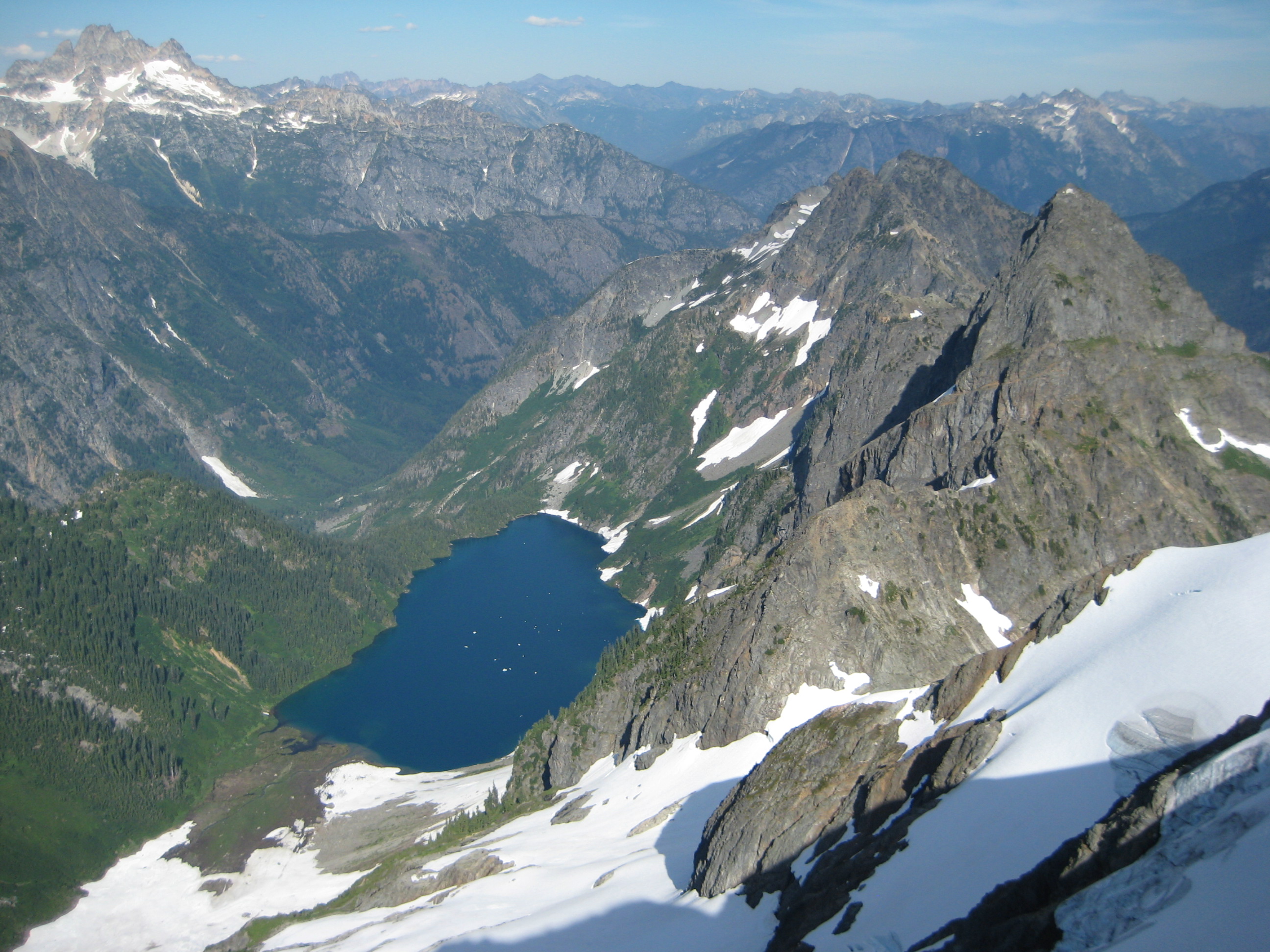 looking down on Trapper Lake with linguring snow fields as seen from the summit of Hurry-Up Peak at the start of the Ptarmigan Traverse