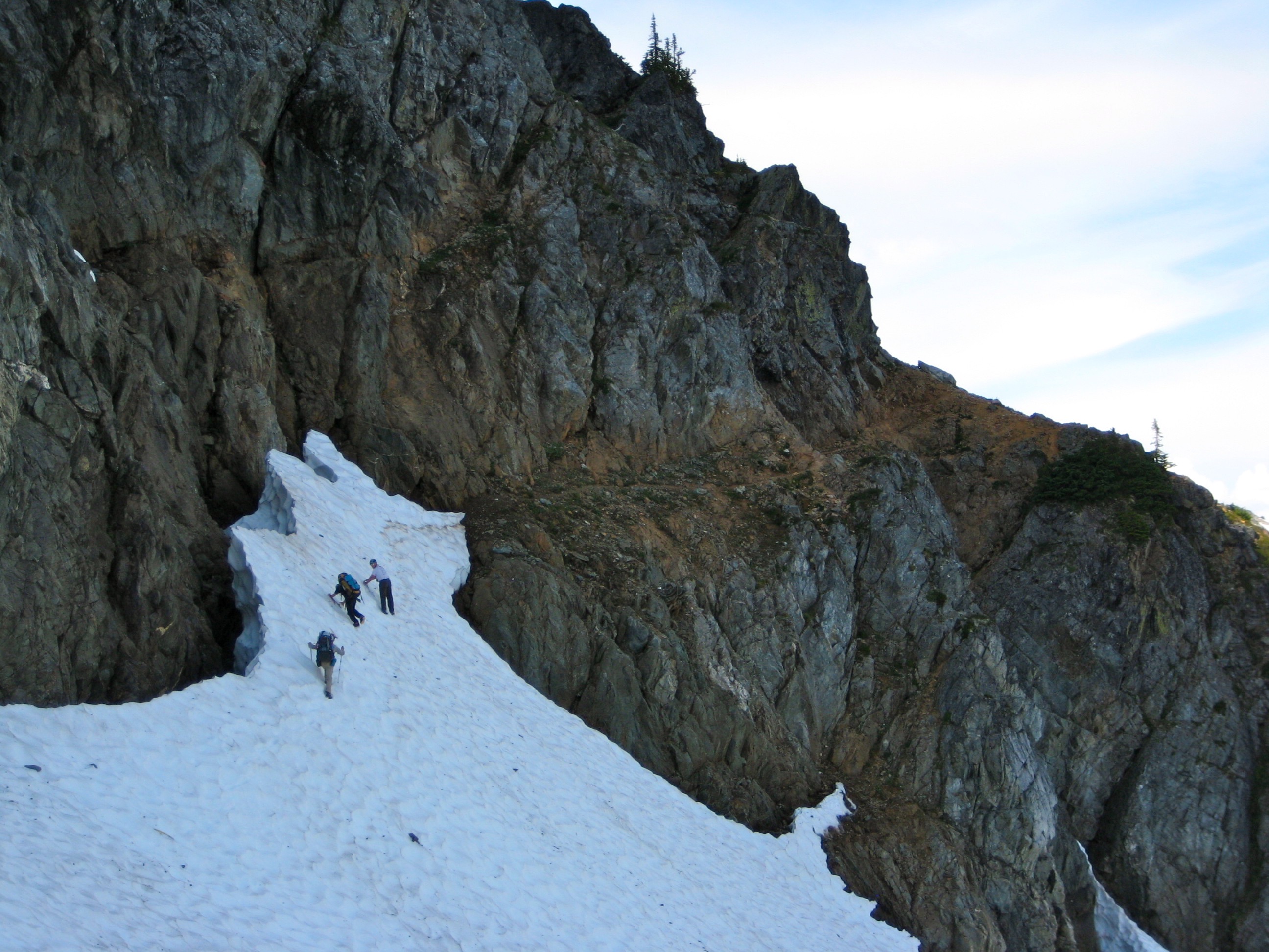 mountain climbers crossing snow field heading to the rocky red ledges on the Ptarmigan Traverse