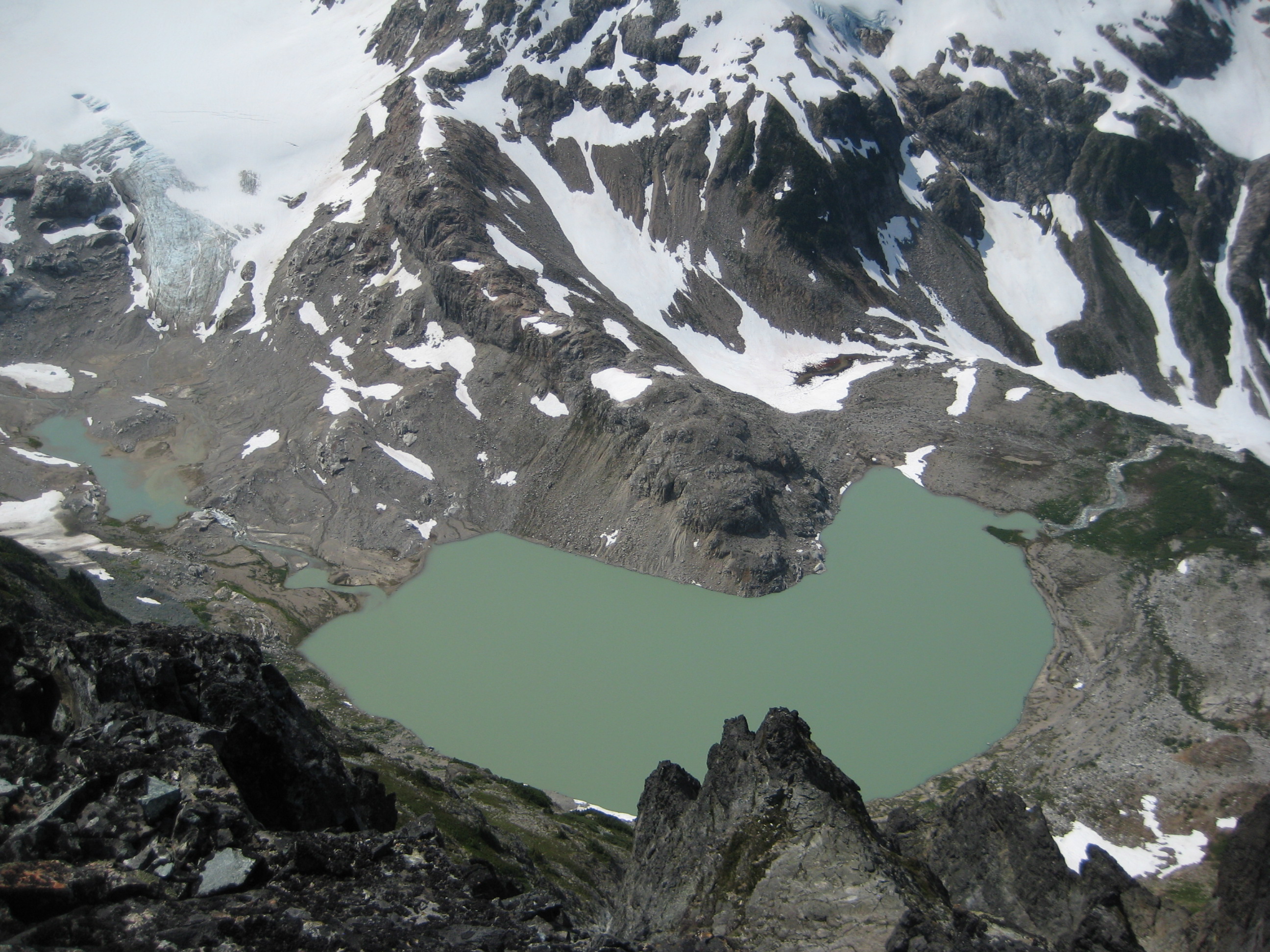 looking down on South Cascade Lake with linguring snow patches as seen from LeConte Mountain