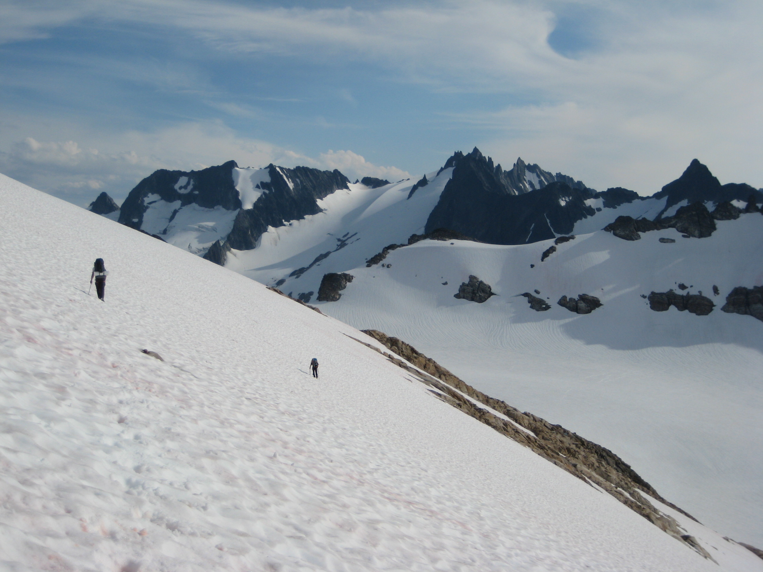 mountain climbers traversing large snow field at Lizard Pass with Ptarmigan Mountains in the background