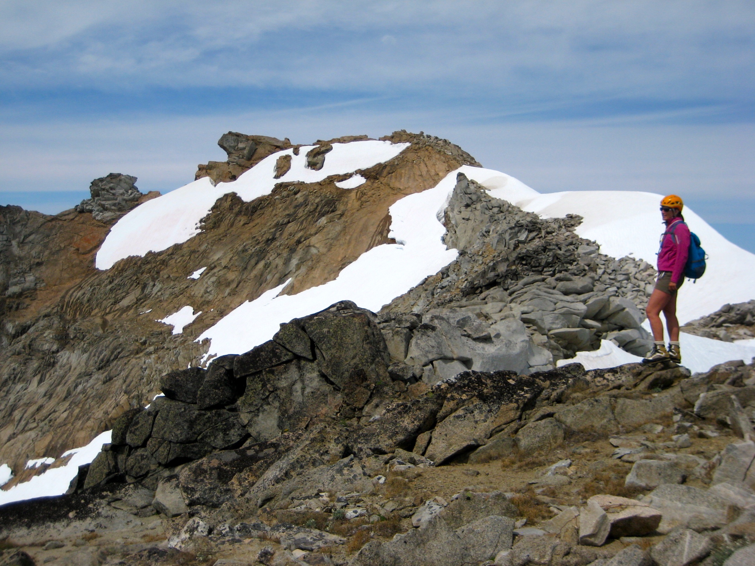 mountain climber and the summit of Dome Peak with linguring snow patches on the Glacier Peak Wilderness