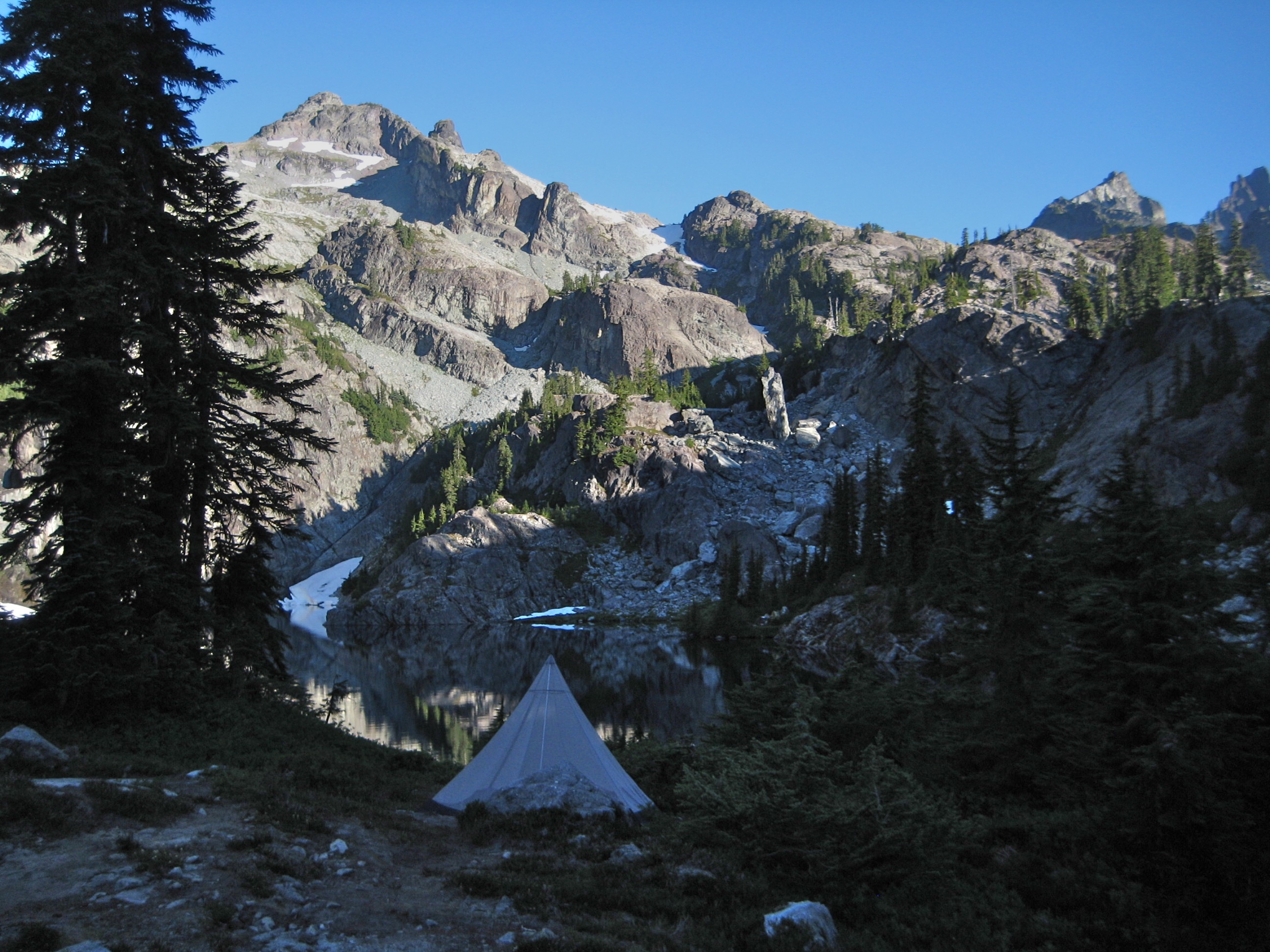 A camping tent is pitched below the rocky summit of Chikamin Peak in the Alpine Lakes WIlderness