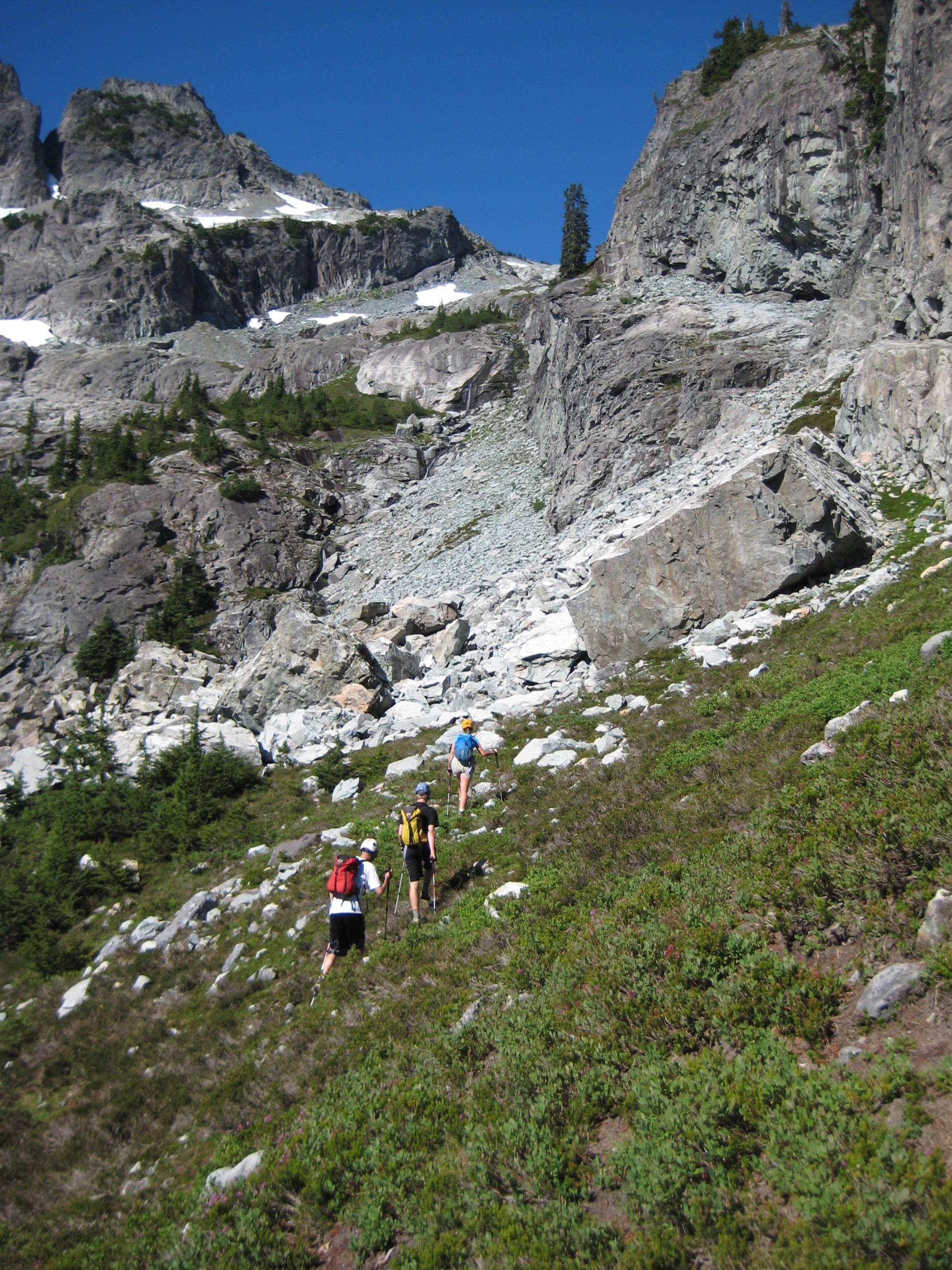 climbers heading up Chikamin Peak via heather slopes with rocky cliffs