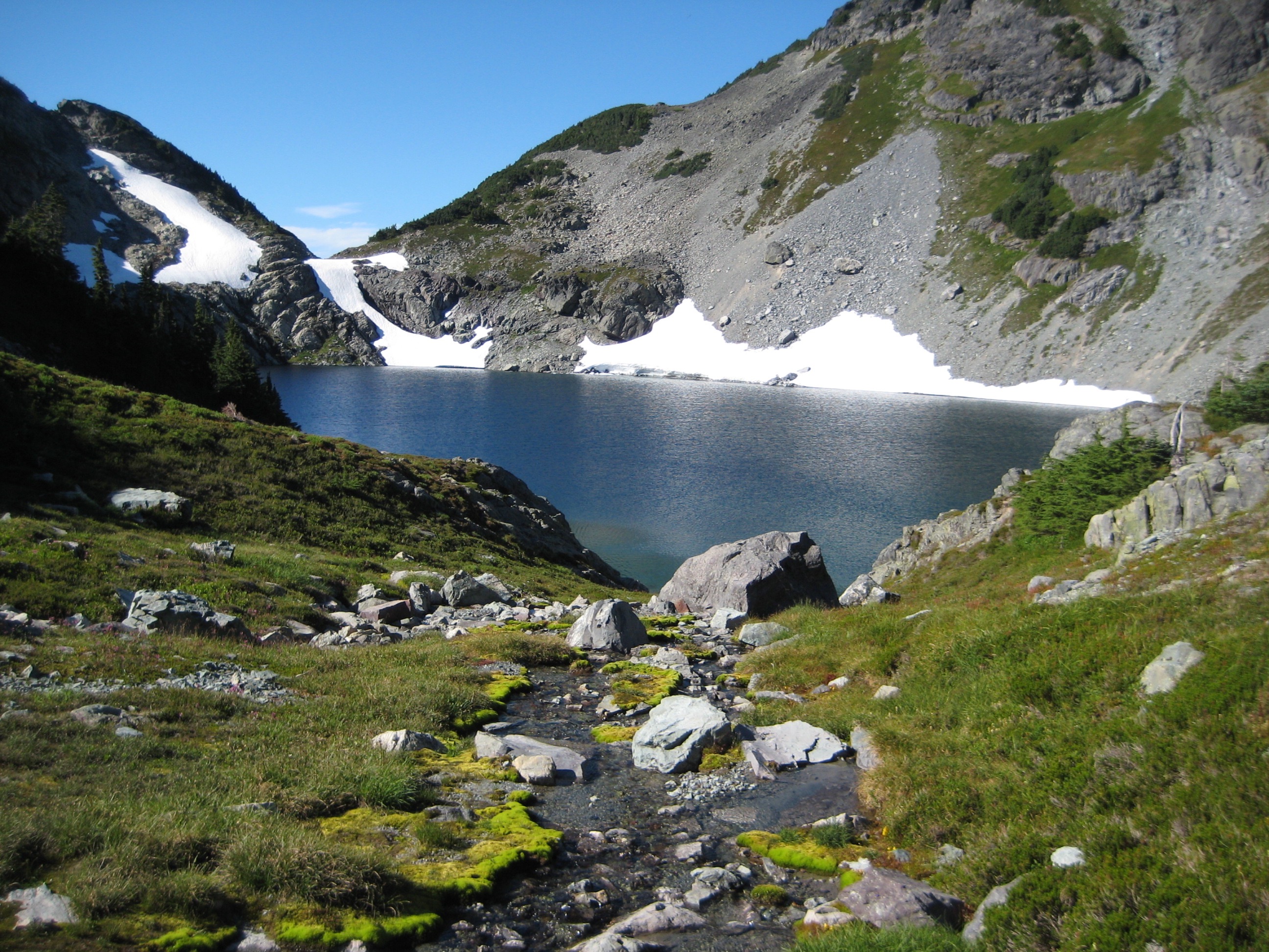 Chikamin Lake Inlet stream with lingering snow patches and rocky shores