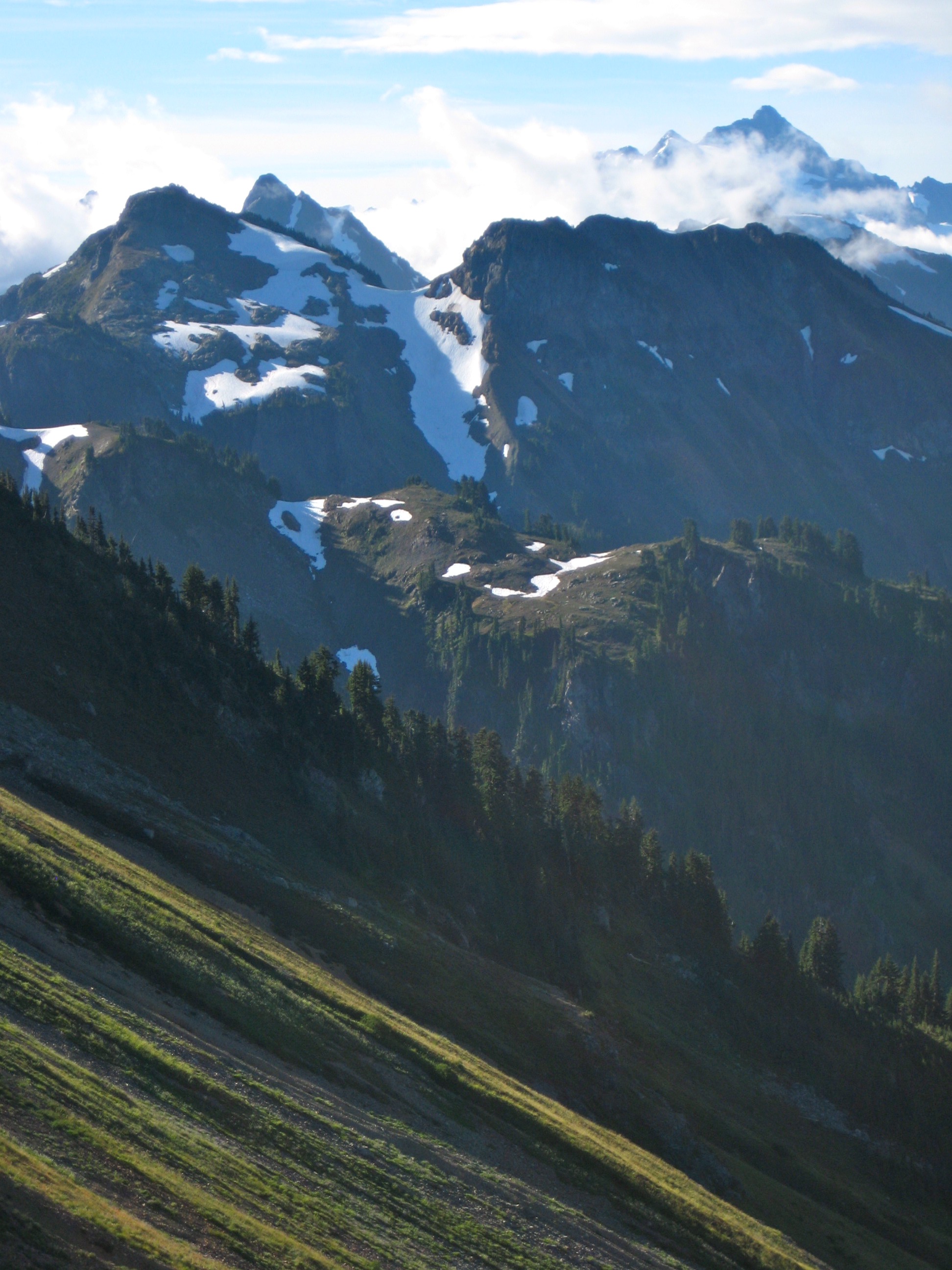 Winchester Mountain and Mt Shuksan with snow patches with steep grassy slopes in the Mt Baker Wilderness