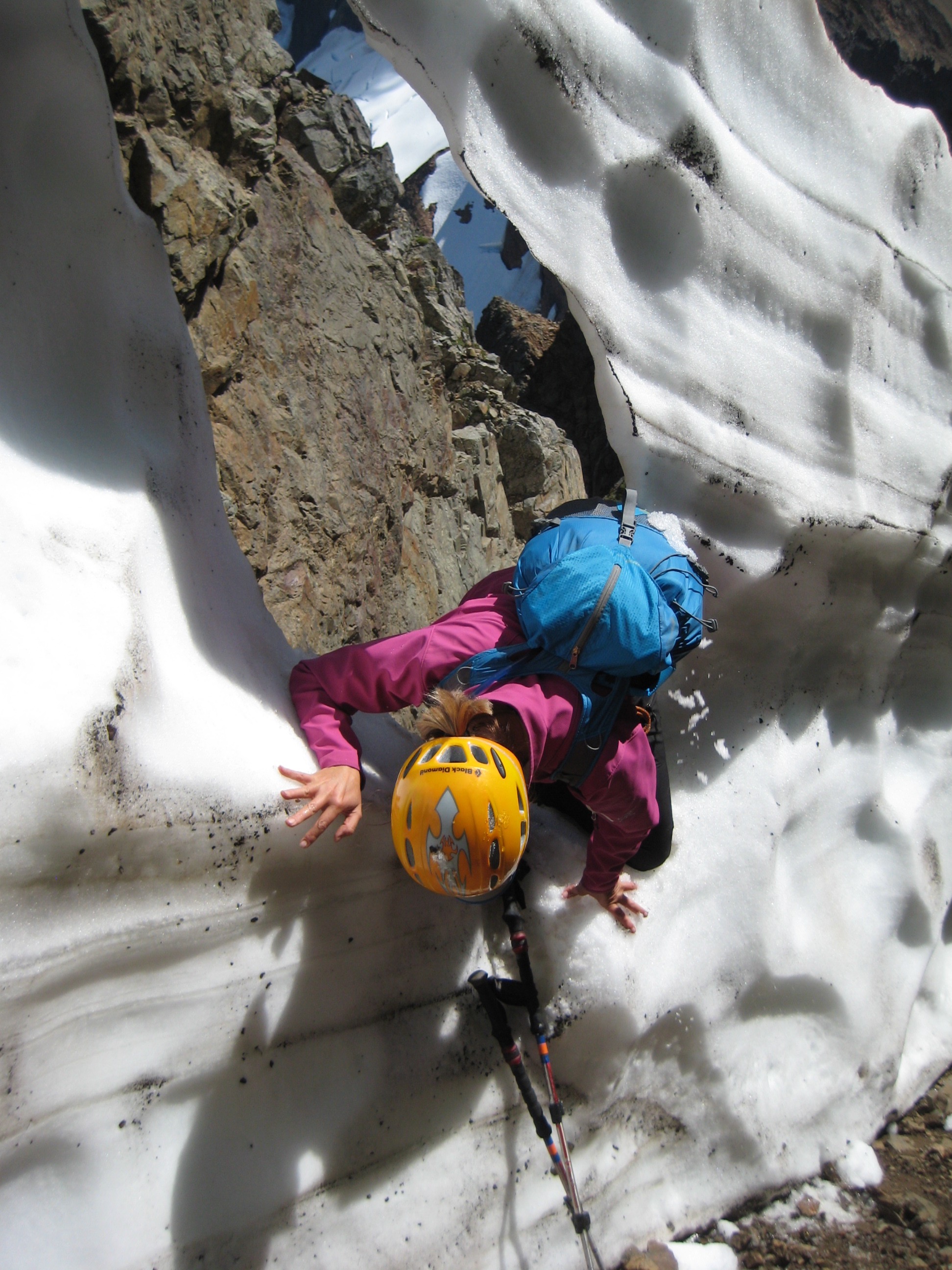 mountain climber crawling through a snow cannonhole on American Border Peak